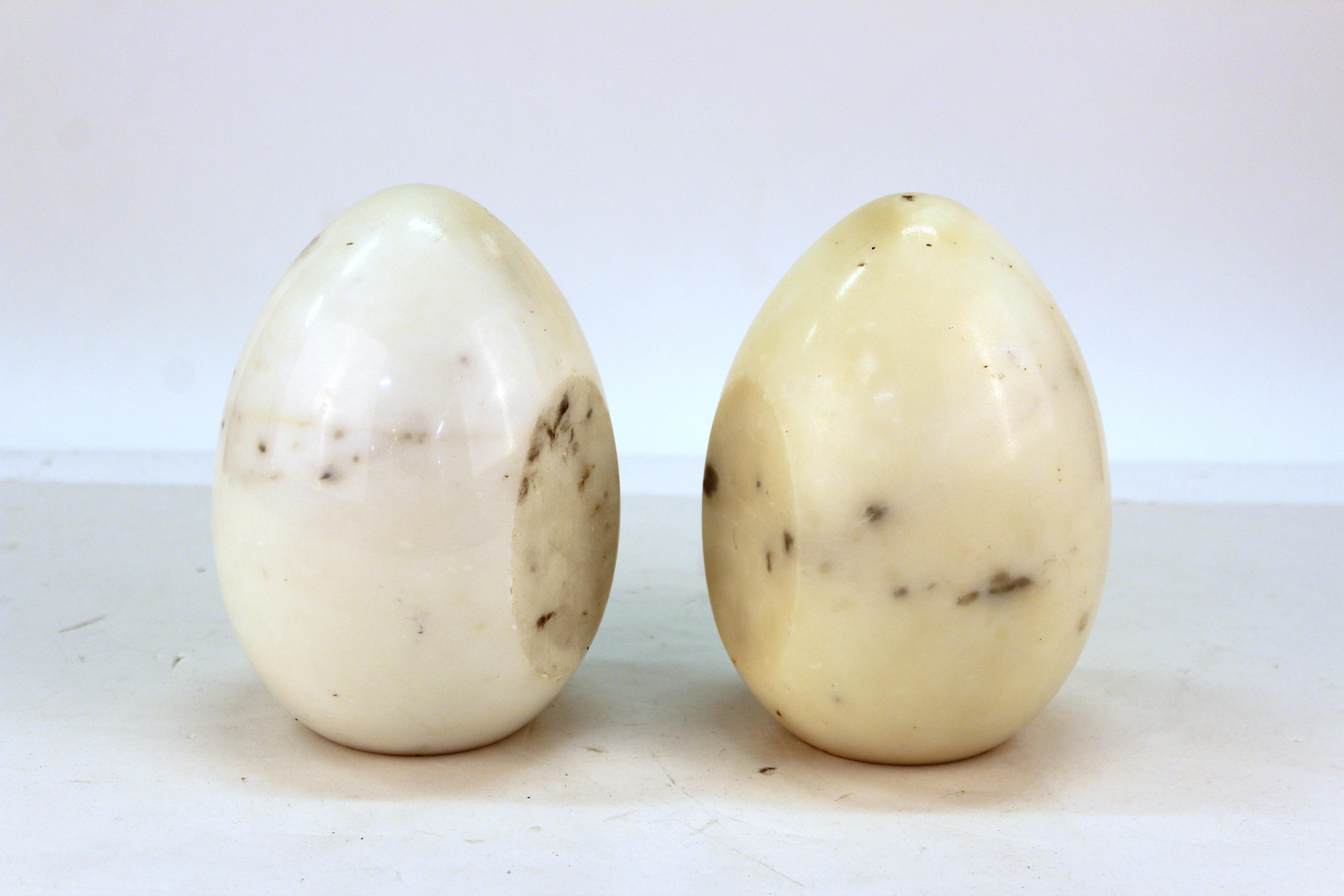 Pair of Mid-Century Modern bookends in the shape of two eggs, sculpted in off-white marble. The pair is in good vintage condition with age-appropriate wear to the bottom and patina to the marble.