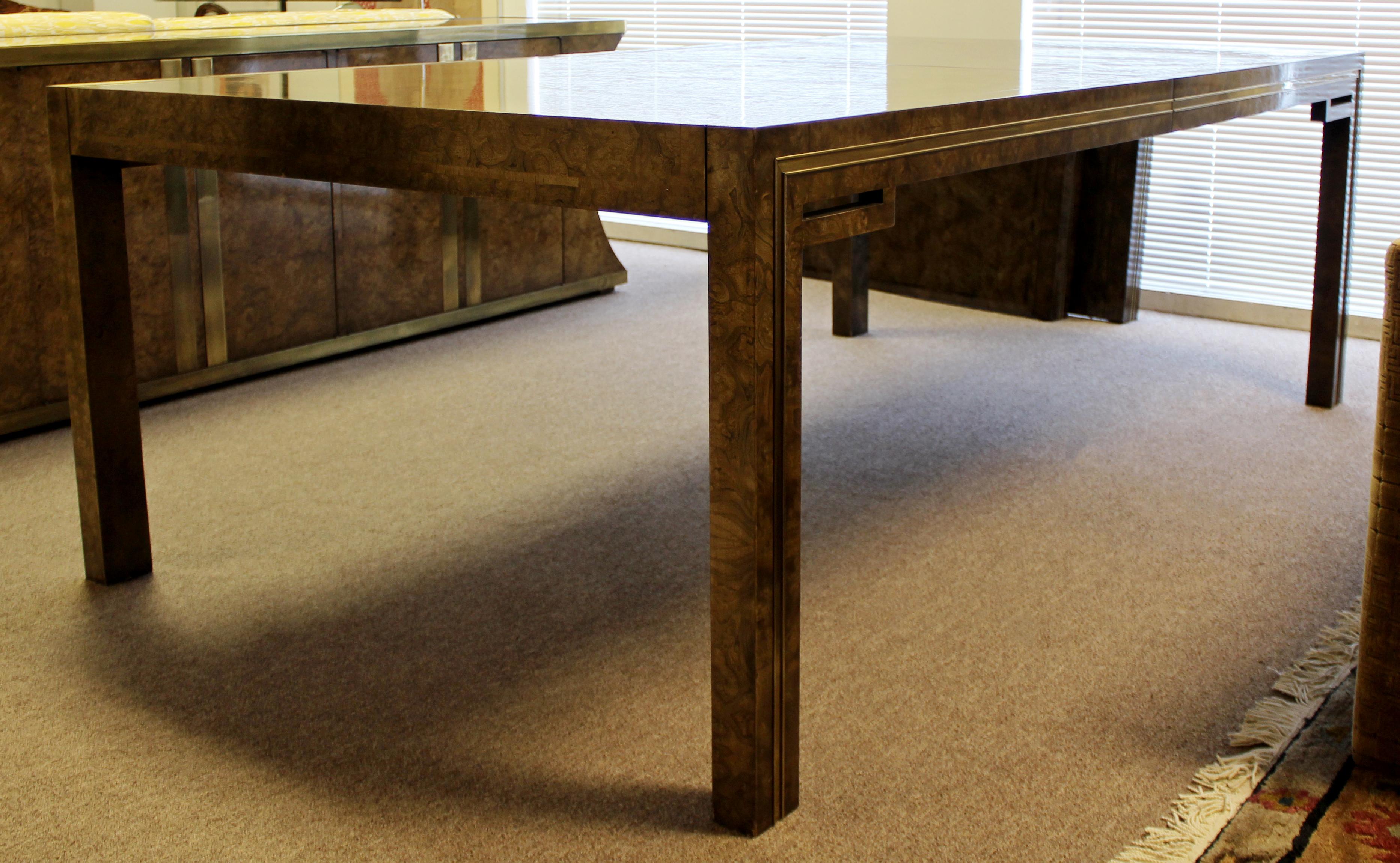 For your consideration is a magnificent, amboyna burl veneer dining table, with brass accents, by Mastercraft, circa 1970s. Includes two leaves. In excellent vintage condition. The dimensions are 84