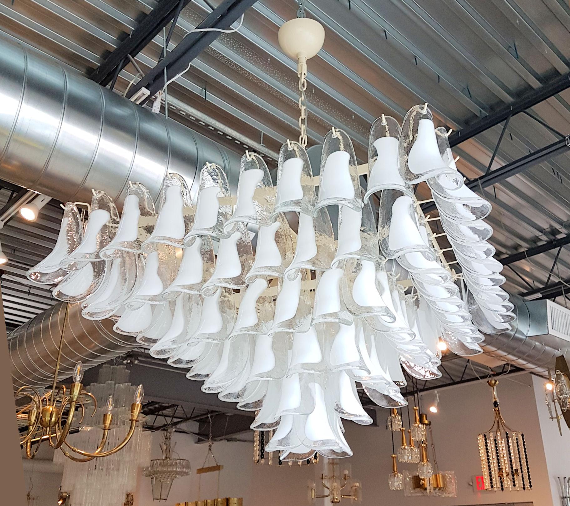 Mid-Century Modern white and clear Murano glass petals chandelier with a square and pyramidal shape.
By Mazzega, Italy, 1970s.
6-tiers Murano chandelier.
8 medium base lights, rewired for US.
Ivory metal frame, chain and canopy.
The white and