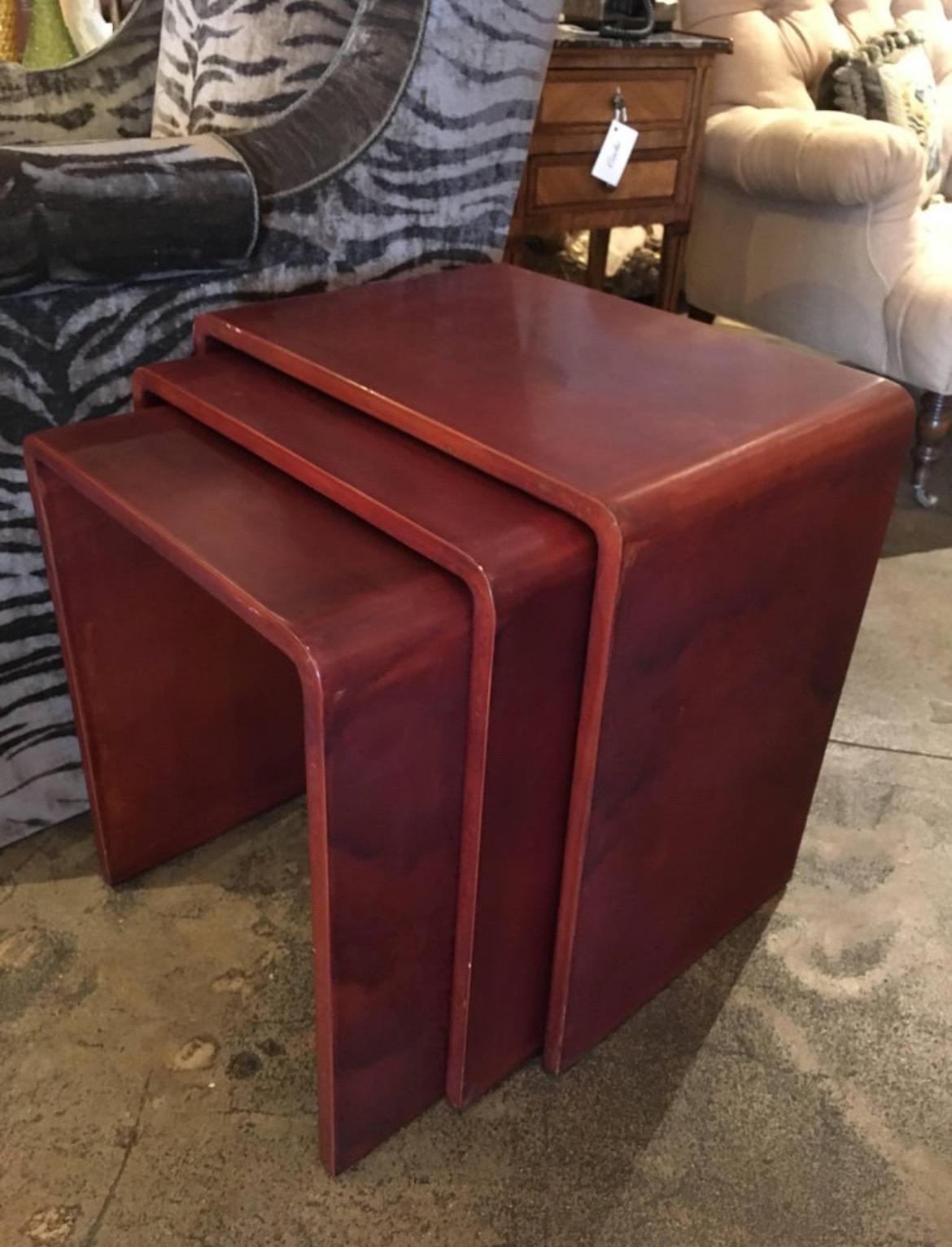 Set of three vintage Mid-Century Modernist waterfall nesting or stacking tables in rare burgundy lacquer finish.

In the style of Jean-Michel Frank
