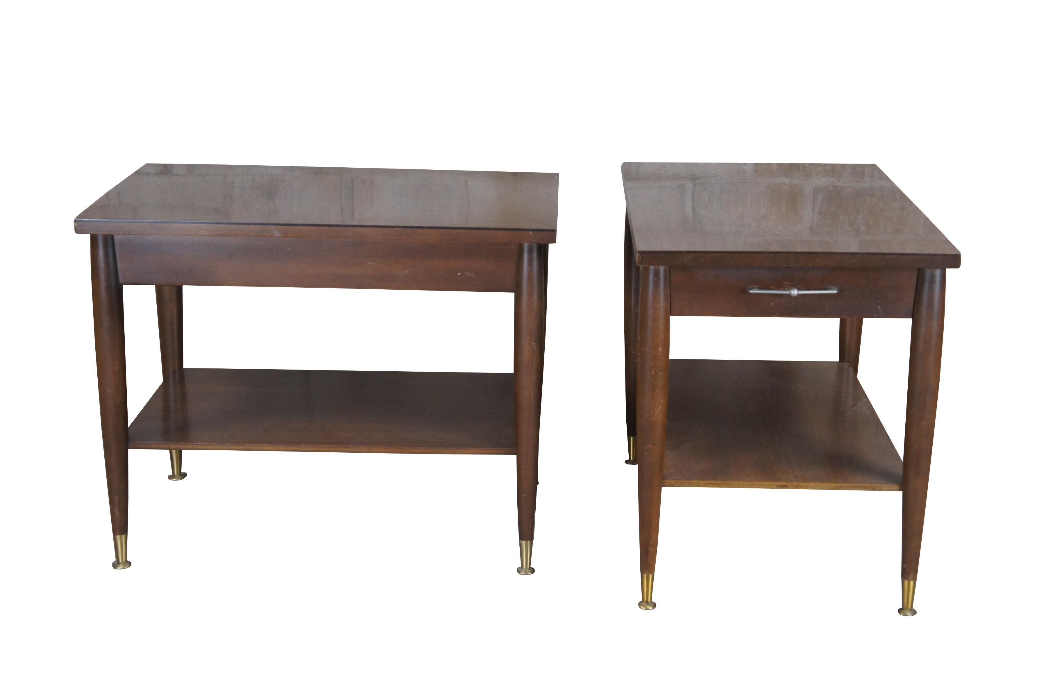 Two mid century modern Mersman end tables.  Made of oak featuring rectangular form with two tier design, one drawer, tapered legs, and brass capped feet.

Dimensions:
27.5