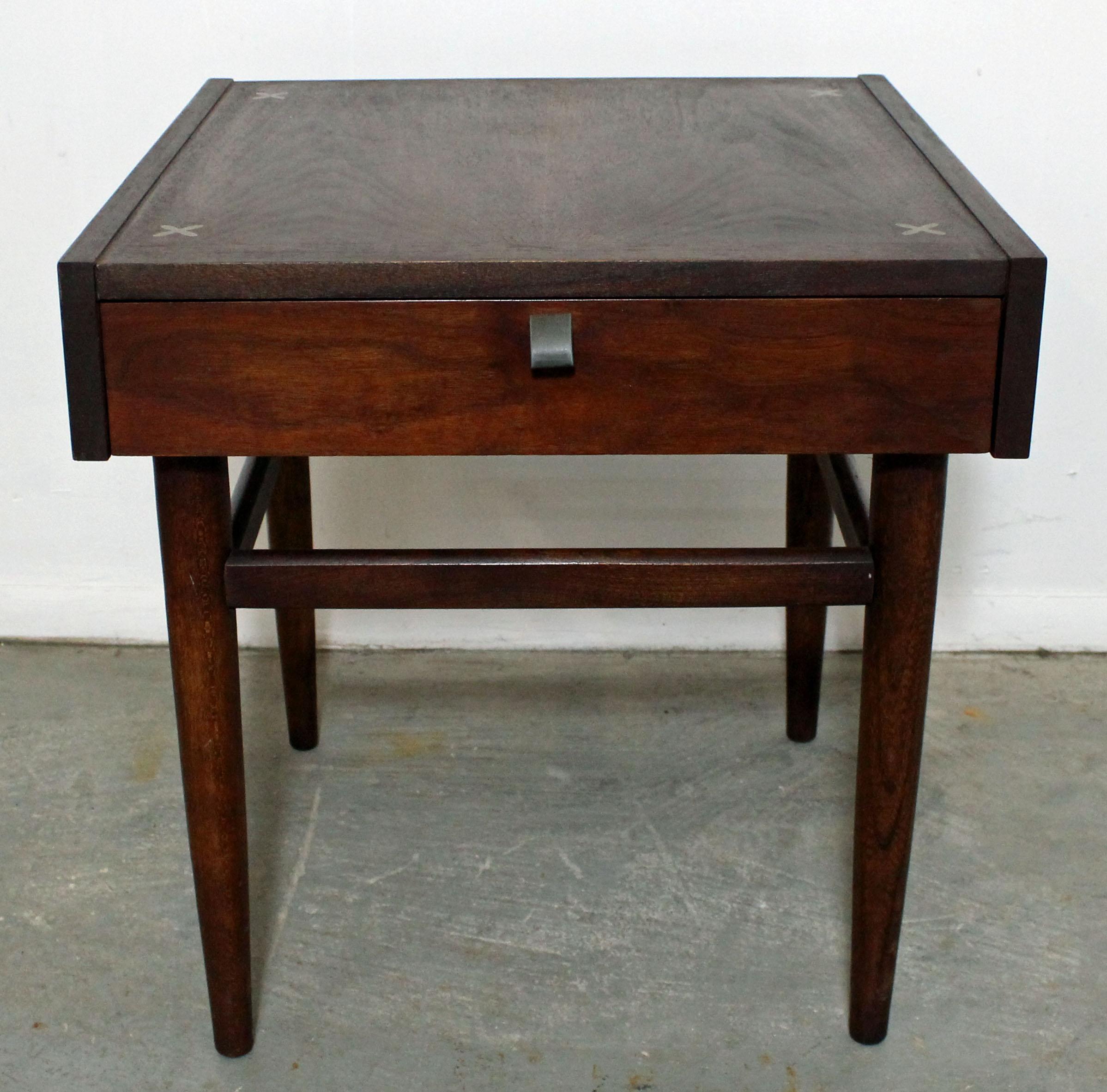 Offered is a walnut end table designed by Merton L. Gershun for American of Martinsville. Features one drawer with a brass pull and the iconic x-shaped brushed aluminium inlaid detailing in the tabletop. It is in very good condition, shows some