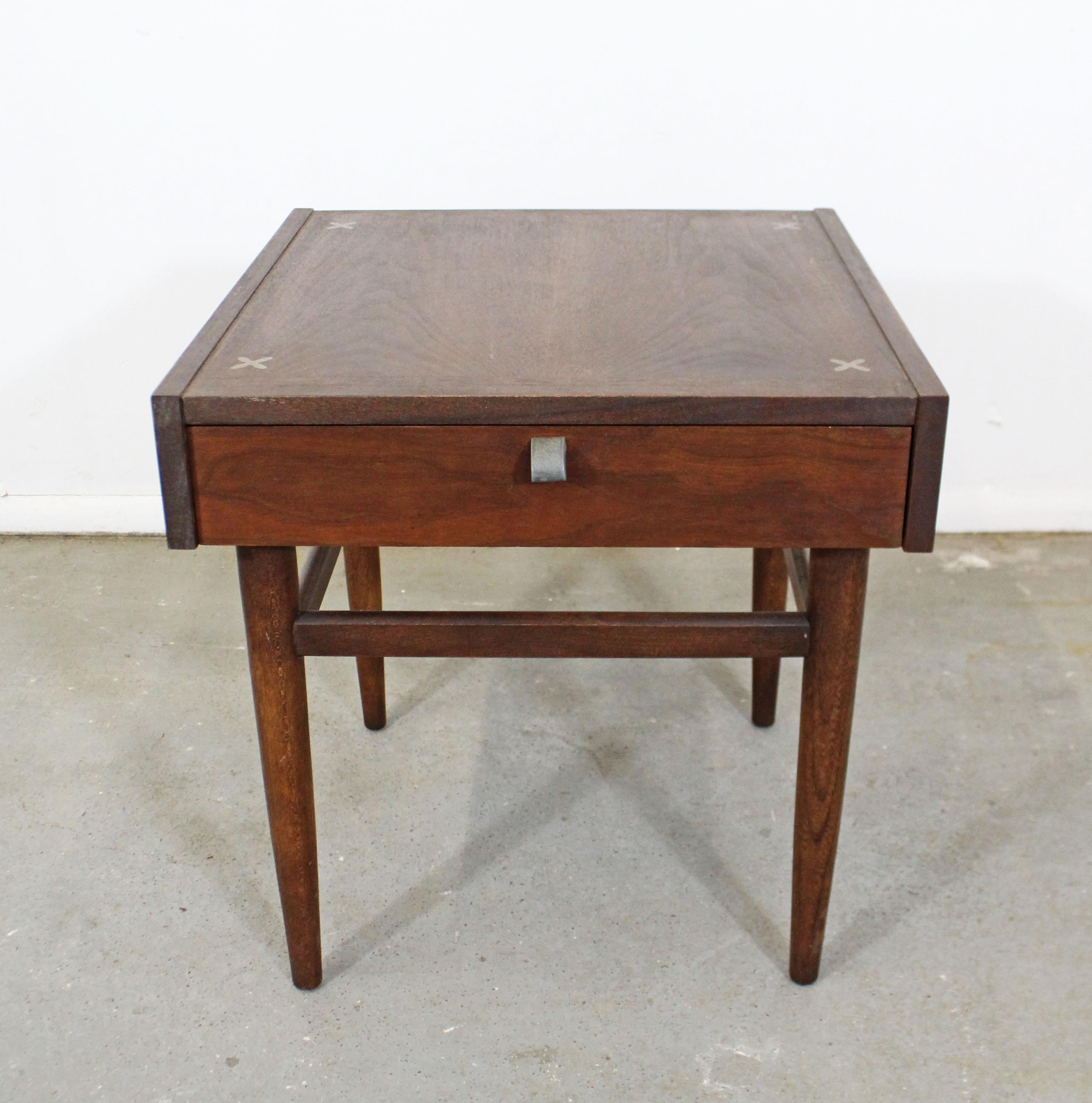 Offered is a vintage Mid-Century Modern walnut end table designed by Merton L. Gershun for American of Martinsville. Includes one drawer with a metal pull and features X-shaped brushed aluminium inlaid detailing in the tabletop. It is in good