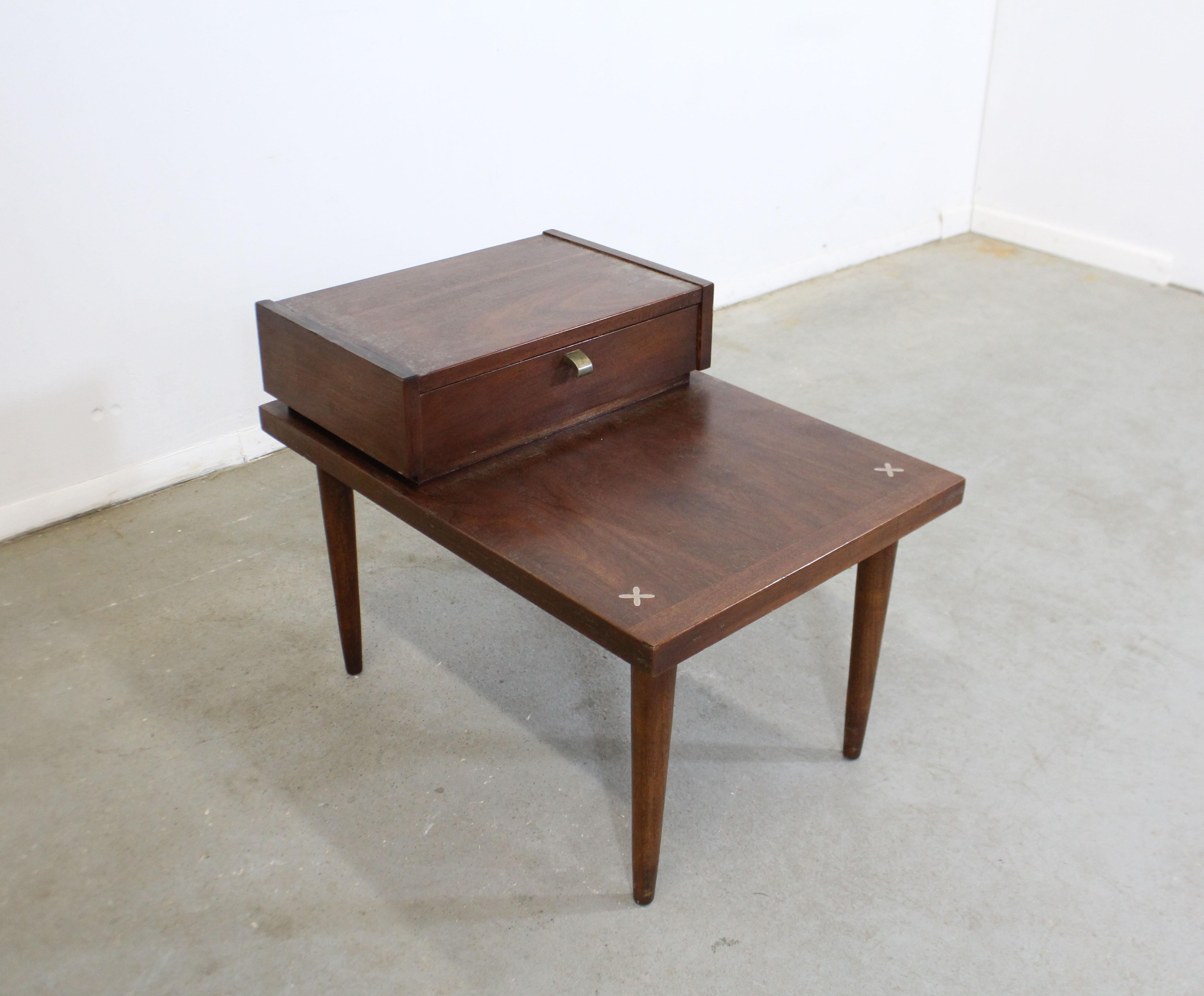 Offered is a vintage walnut end table designed by Merton L. Gershun for American of Martinsville. Features the iconic x-shaped brushed aluminum inlaid detailing in the tabletop. Has one drawer. It is in good condition, shows some slight wear on the