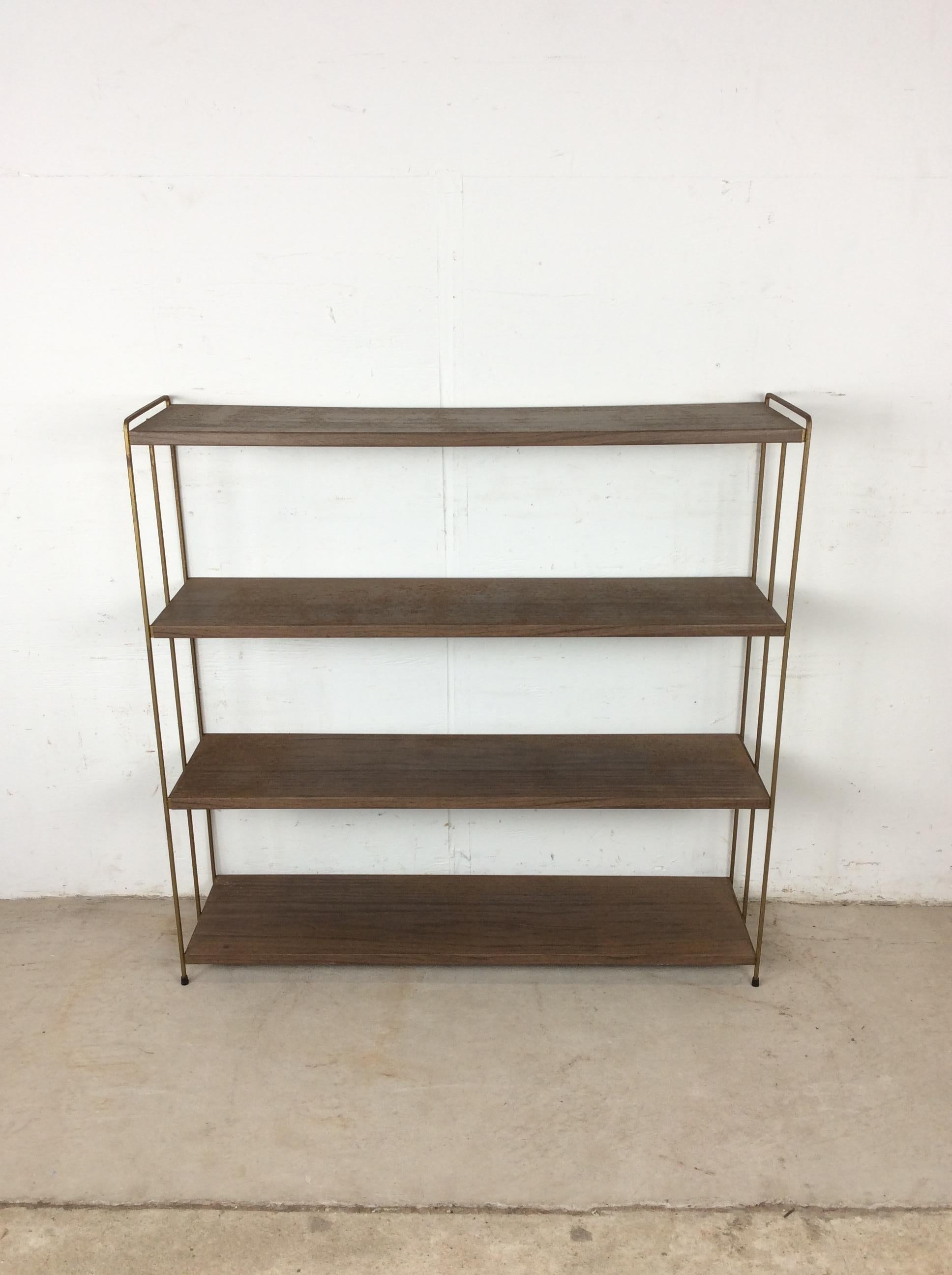 This classic mid century modern bookcase features four metal shelves with original brown paint and faux walnut print, brass accented legs & feet.  I have two more of these identical shelves available and one similar step shelf. Please check out the