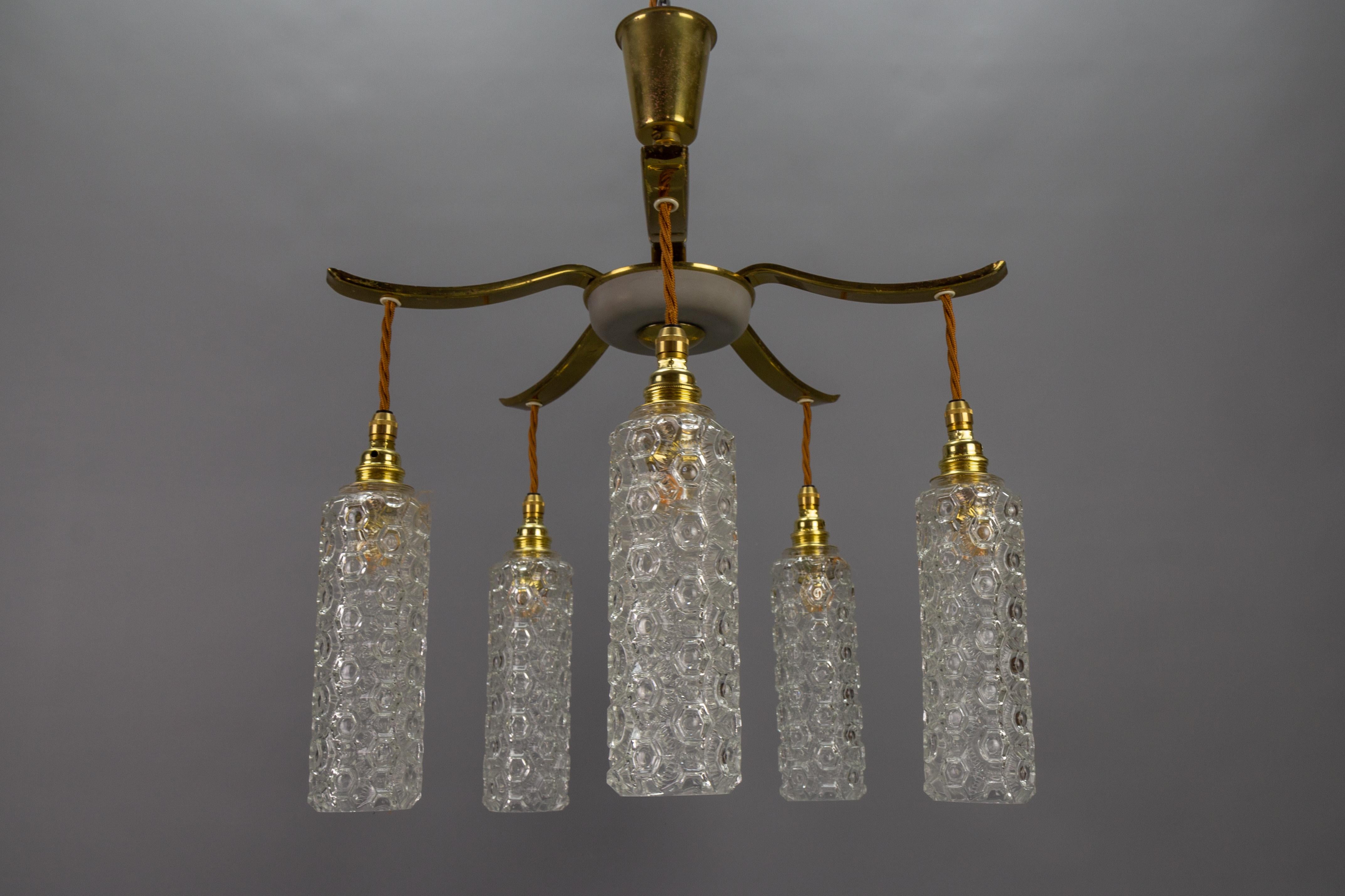 Mid-Century Modern metal and clear glass five-light pendant chandelier, Germany, circa the 1950s.
This adorable vintage pendant chandelier features a brass- and cream-colored metal frame with five arms, each with a clear glass cylinder-shaped