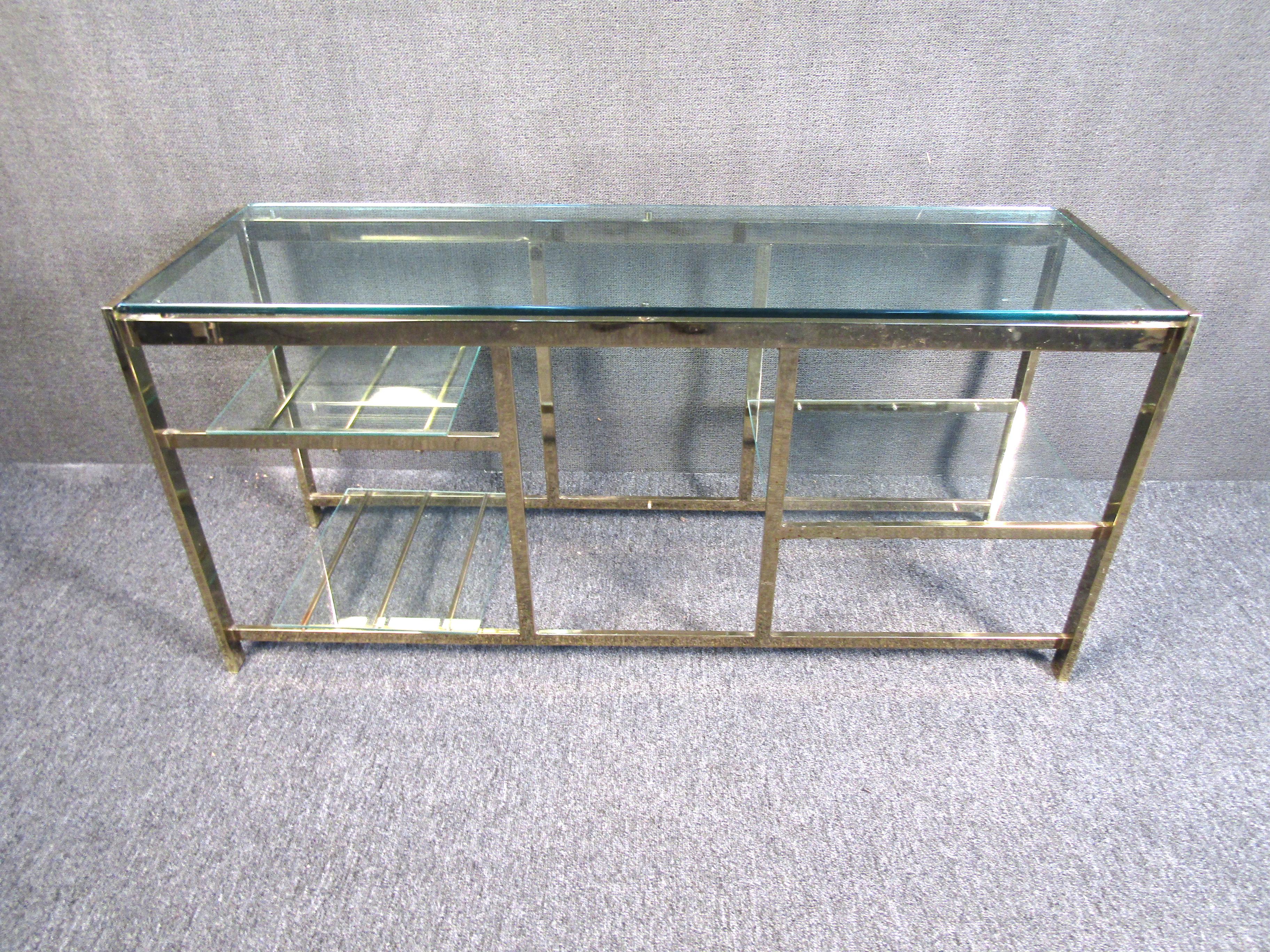 This striking vintage table combines an angular metal frame with glass shelving for a design full of midcentury elegance. A unique table that is perfect for serving guests, displaying decorative items, or adding a modern decorating taste to any