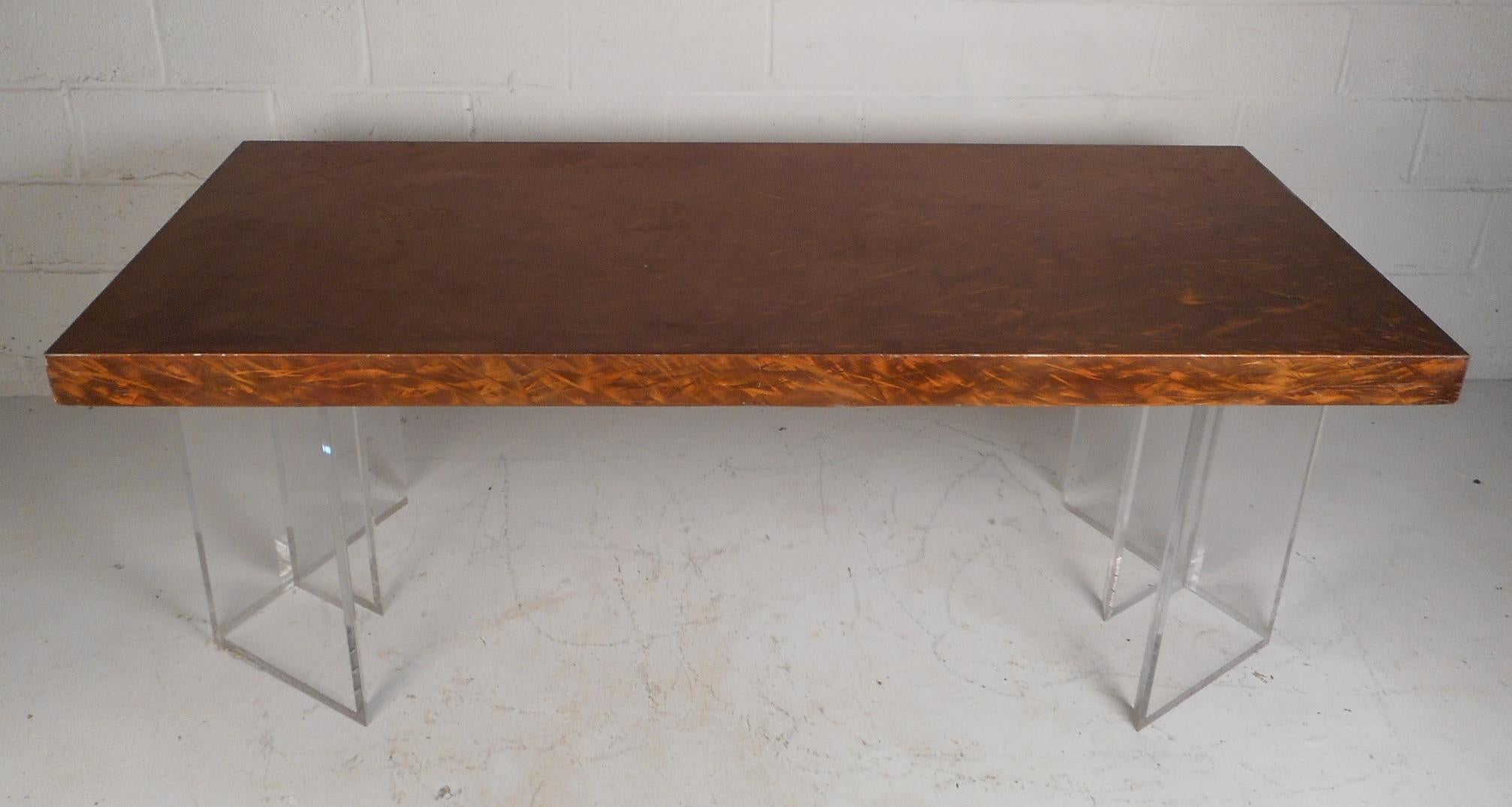 This gorgeous vintage modern dining table features a brushed metal top and a Lucite base. This one of a kind piece has two separate Lucite pieces supporting the table top. A sleek design with a brass and copper colored finish on the top. This table