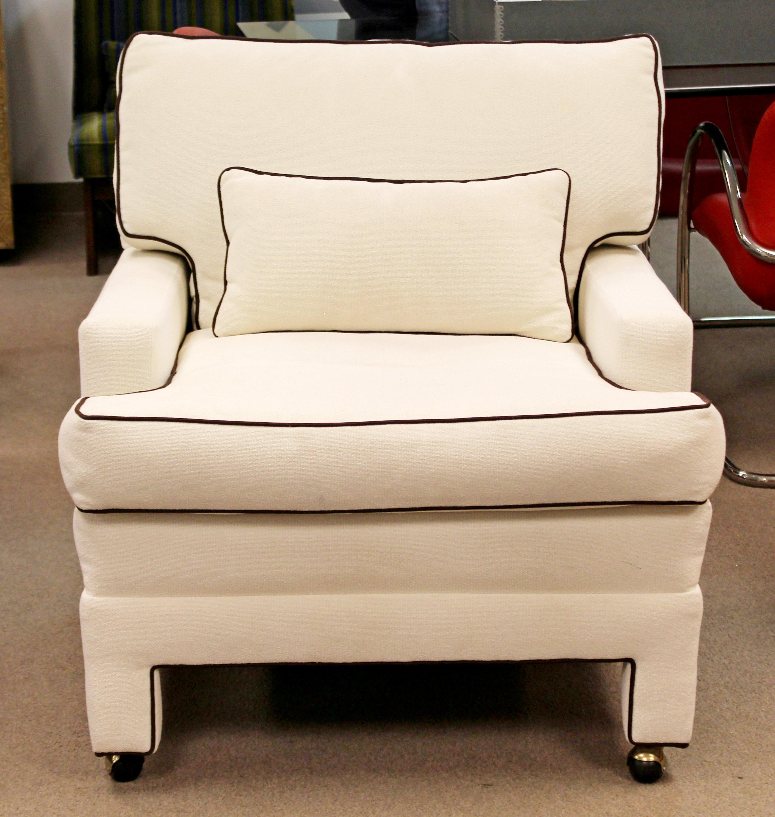 For your consideration is a massive, plush armchair, in a white fabric, with brown trim and brass casters, attributed to Milo Baughman. In excellent condition. The dimensions are 33
