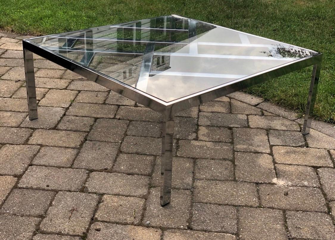 True midcentury period cocktail table made of chrome and glass. Note that there are two chips on the glass as shown and the piece has been priced commensurately with flaws. Chrome shows well and does have slight wear. This is a DIA, Design Institute