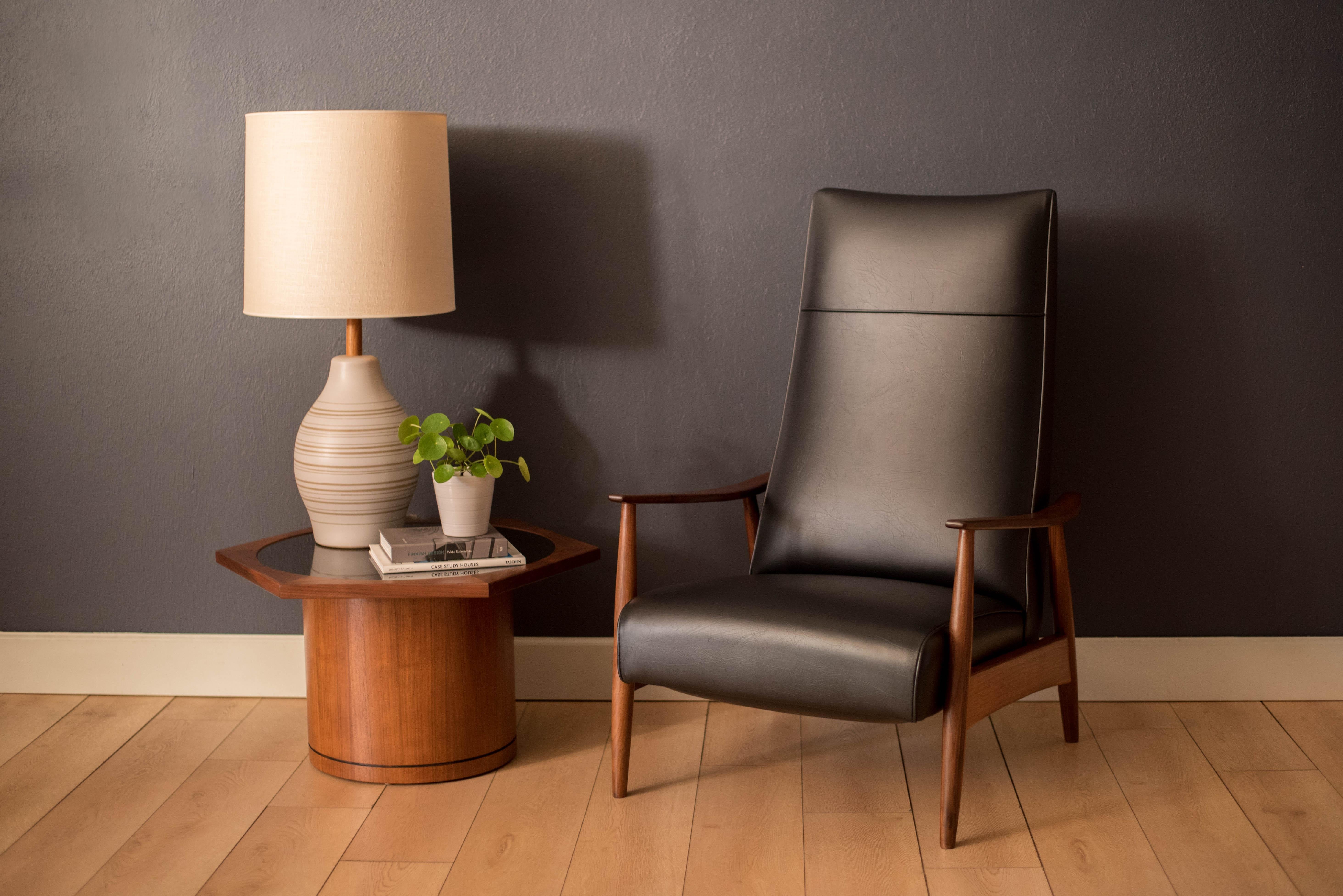 Vintage high back reclining lounge chair model no. 74 designed by Milo Baughman for James Inc. This piece is constructed of solid walnut and has been professionally reupholstered in black vinyl. Lean back for two alternate reclining positions.