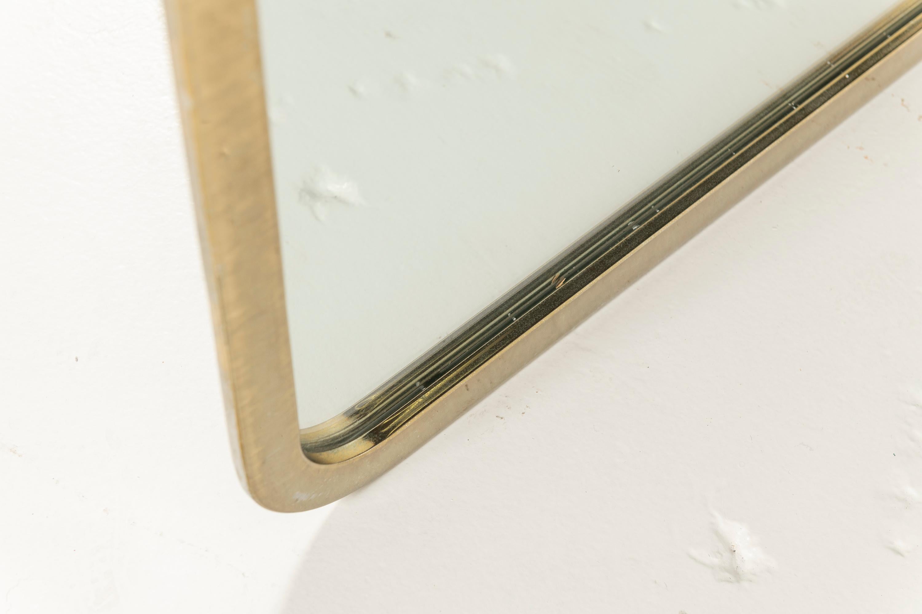 Milo Baughman is most known for his furniture designs of the late 20th Century, especially his lounge chairs. To accompany these pieces, he designed accessories with the same distinct flair. Thr mirror has a brass, rounded edged frame, indicative of