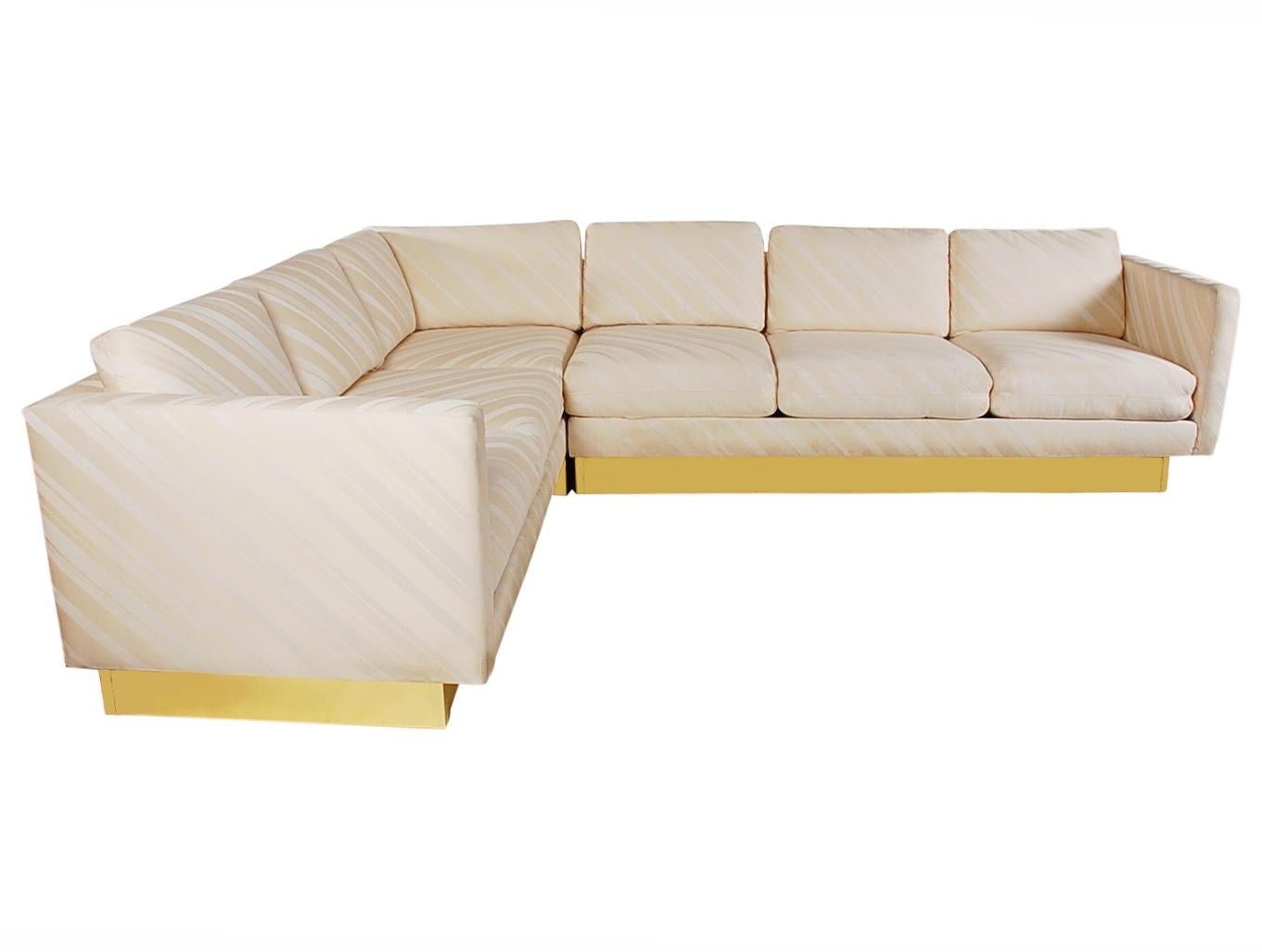 A lovely and chic looking sectional sofa attributed to Milo Baughman for Thayer Coggin. This L shaped sofa features it's original cream colored upholstery and brass-clad base.