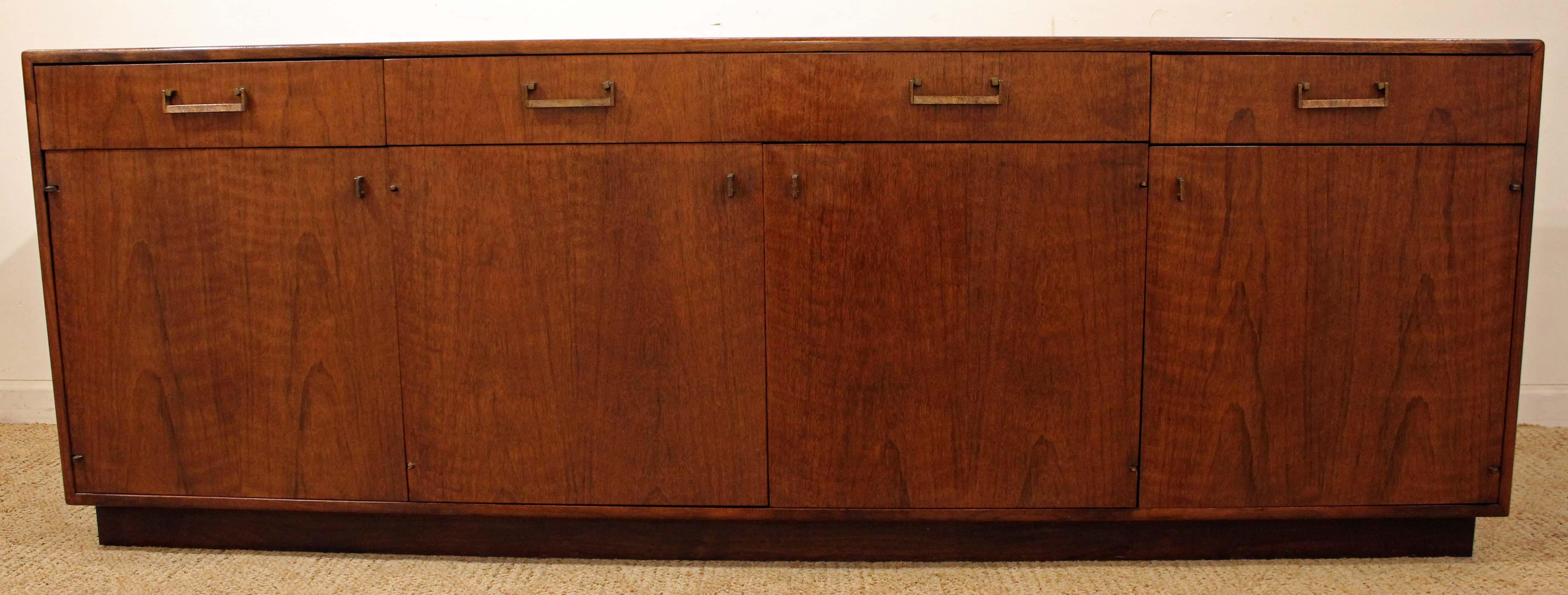 Offered is a Mid-Century Modern credenza, we believe is designed by Milo Baughman for Founders. It is made of walnut with brass pulls, featuring three dovetailed drawers up top and four doors with shelving for ample storage inside. It is in