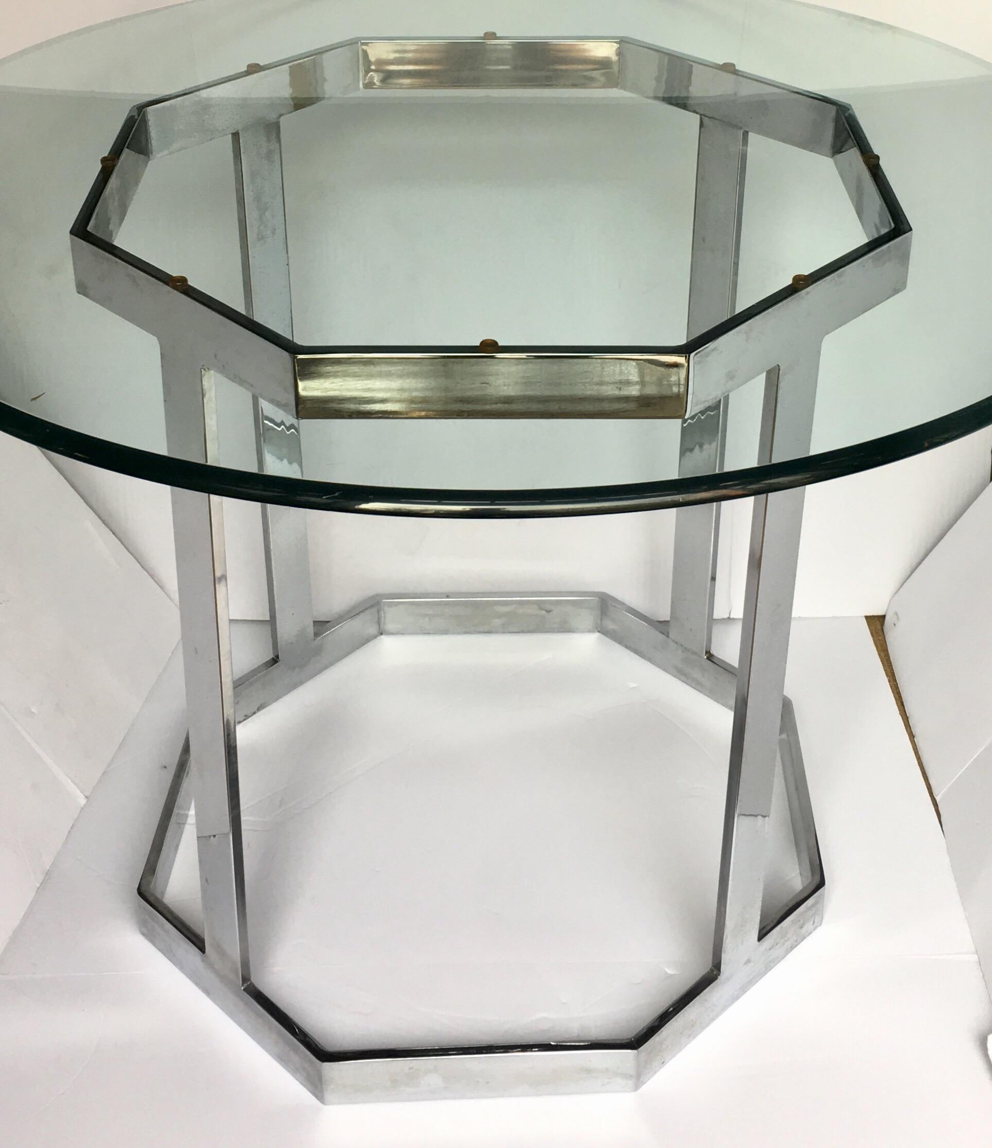1970s Mid-Century Modern chrome and glass dining or center table in the style of Milo Baughman. Sculptural polished chrome base features a flat bar octagon design. Existing round clear glass top is removable and can be replaced with a larger size
