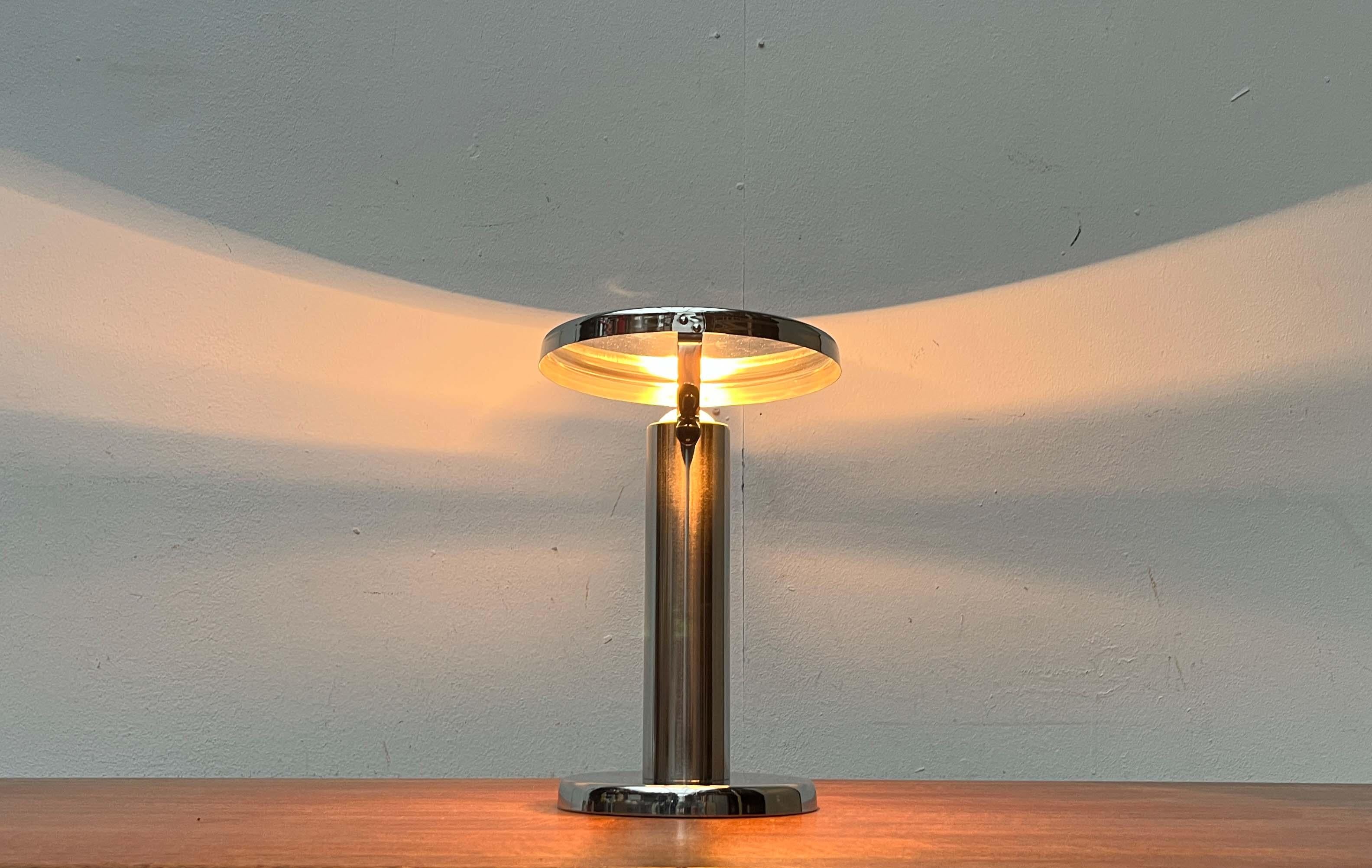 Minimalist table lamp with movable head.

A functionalist design. The lamp consists of a cylindrical tube as a base, which ends in a plate foot at the bottom. The socket is located inside the tube. Half of the light bulb protrudes from the base. The