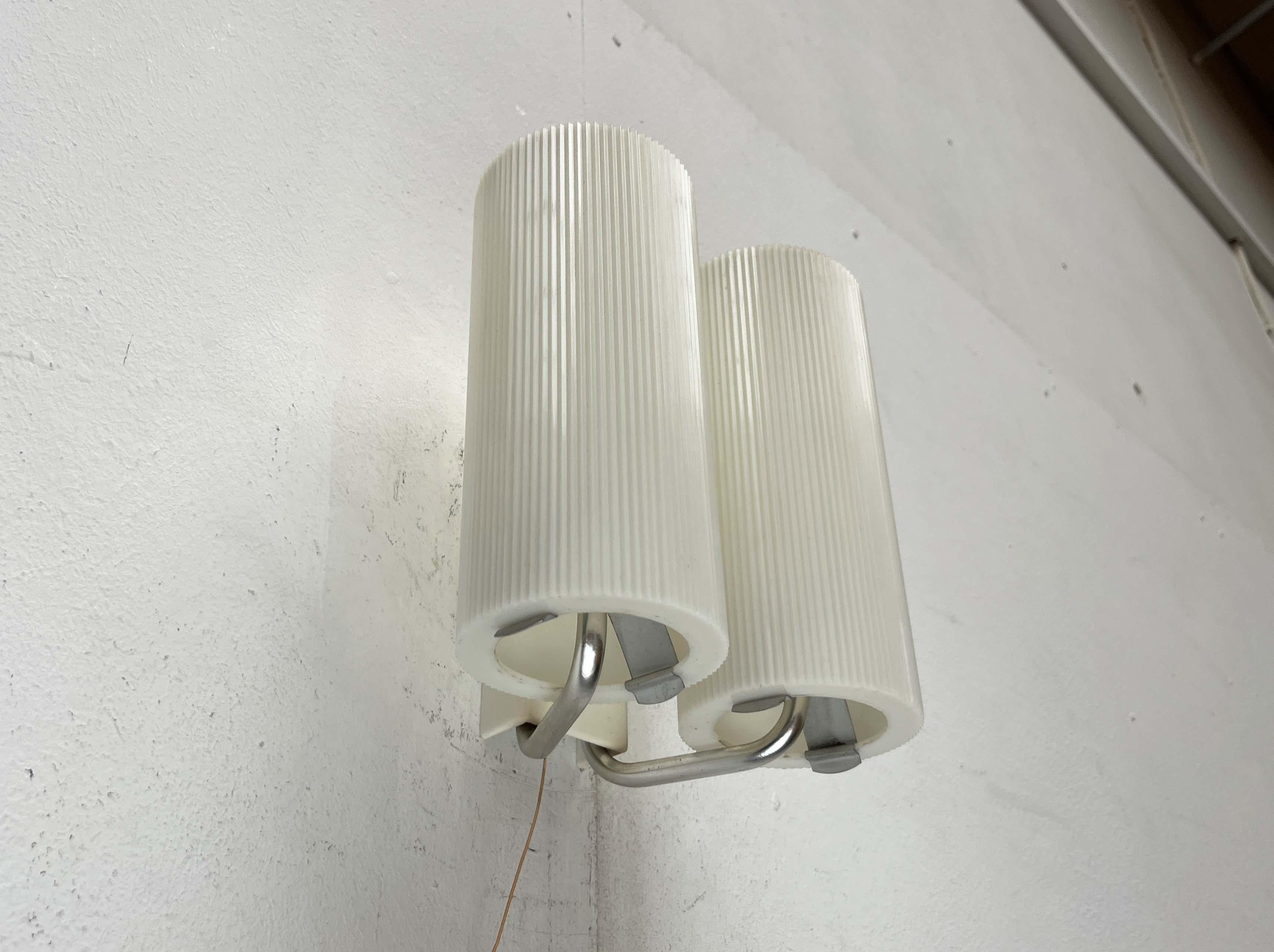 Rara lámpara de pared de Erco.

Un diseño minimalista. Las pantallas cilíndricas son de plástico. Presentan una superficie estriada, que proporciona una luz difusa y antideslumbrante adicional. Las persianas se fijan en la parte inferior con