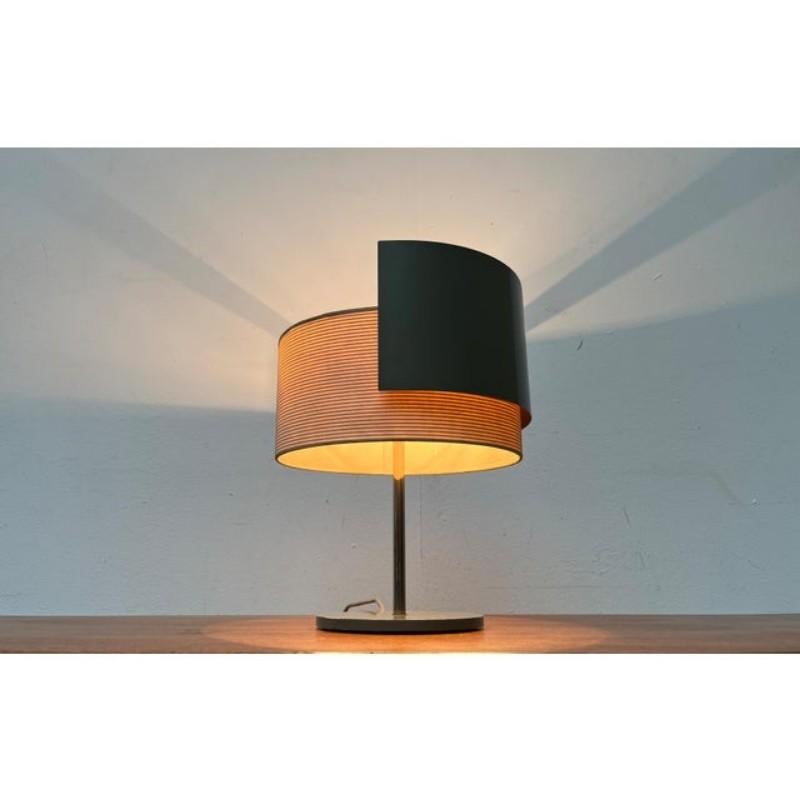 Tischlampe aus der Mitte des Jahrhunderts mit beweglichem Schirm.

Ein minimalistisches Design. Die Leuchte hat eine einfache Grundform mit einem trommelförmigen Schirm und einem Tellerfuß. Oben auf der Welle ist eine Blende angebracht. Der Schirm