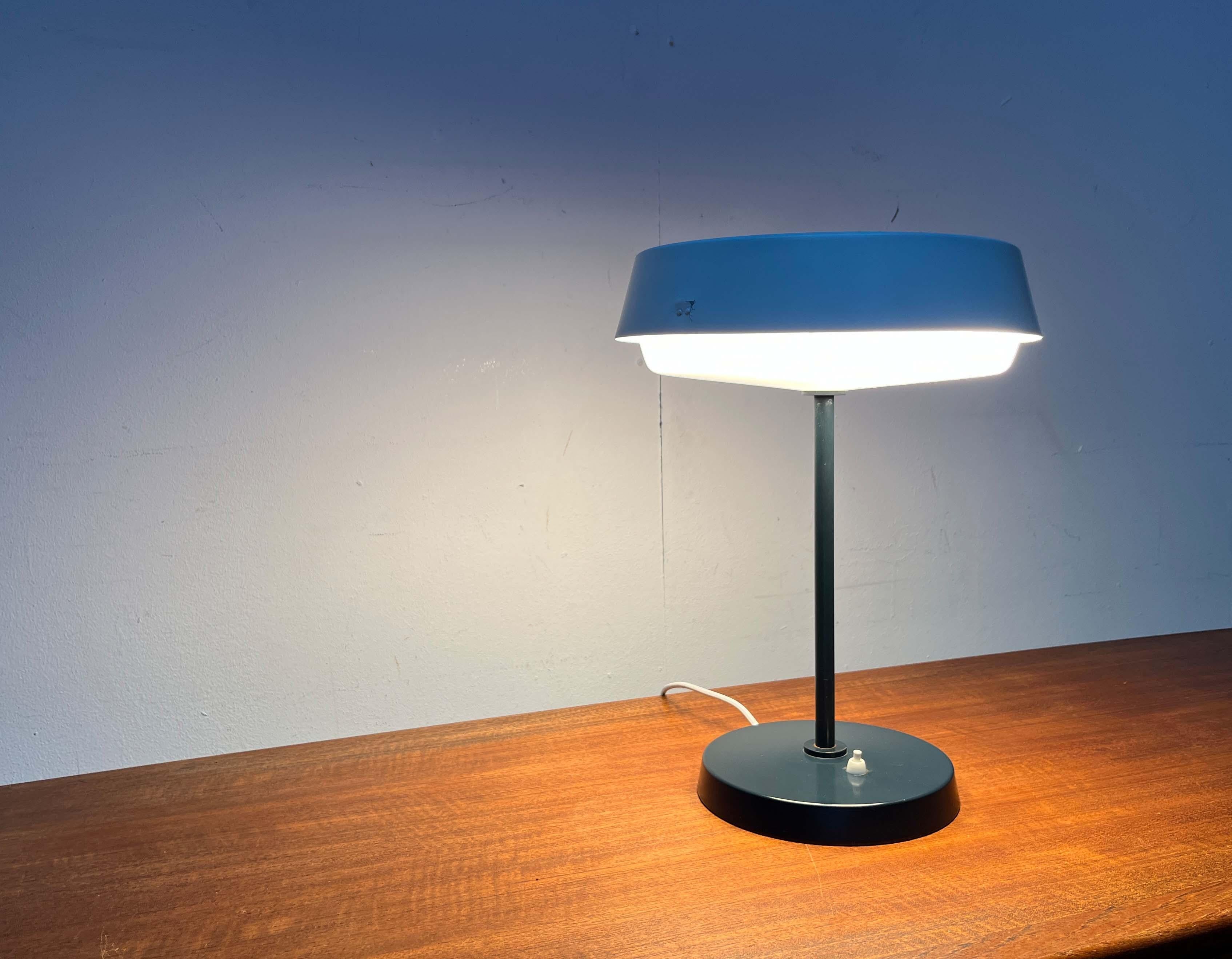 Minimalist table lamp by the traditional Finnish company Idman, based on a design by Voitto Haapalainen from the 1950s. An original from the Aalto era.

A classic of Finnish mid-century design. The lamp consists of a round lamp head connected to a