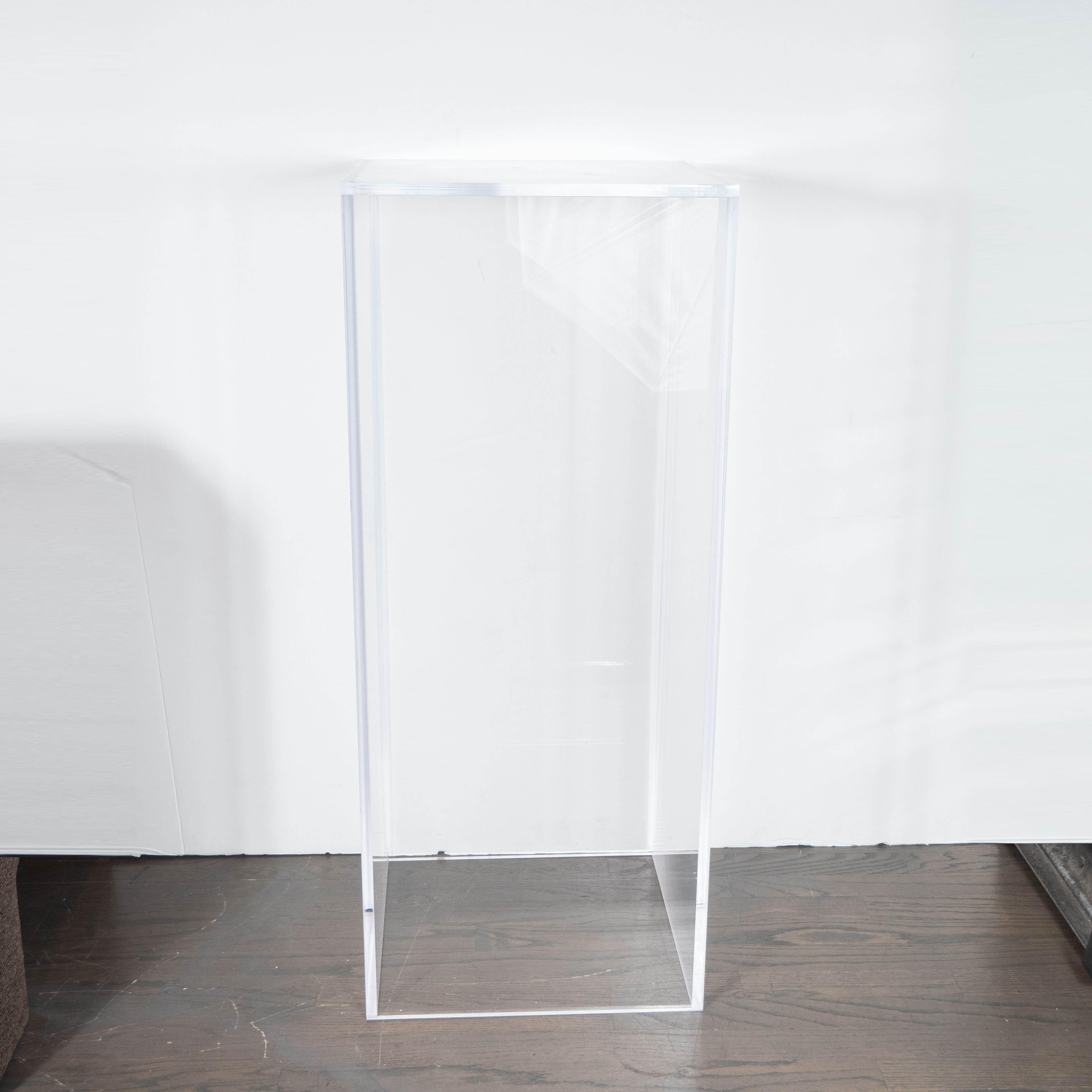 This elegant and austere Mid-Century Modern pedestal was realized in the United States in the latter half of the 20th century. It features a volumetric rectangular form created in translucent Lucite. With its clean lines and austere silhouette, this