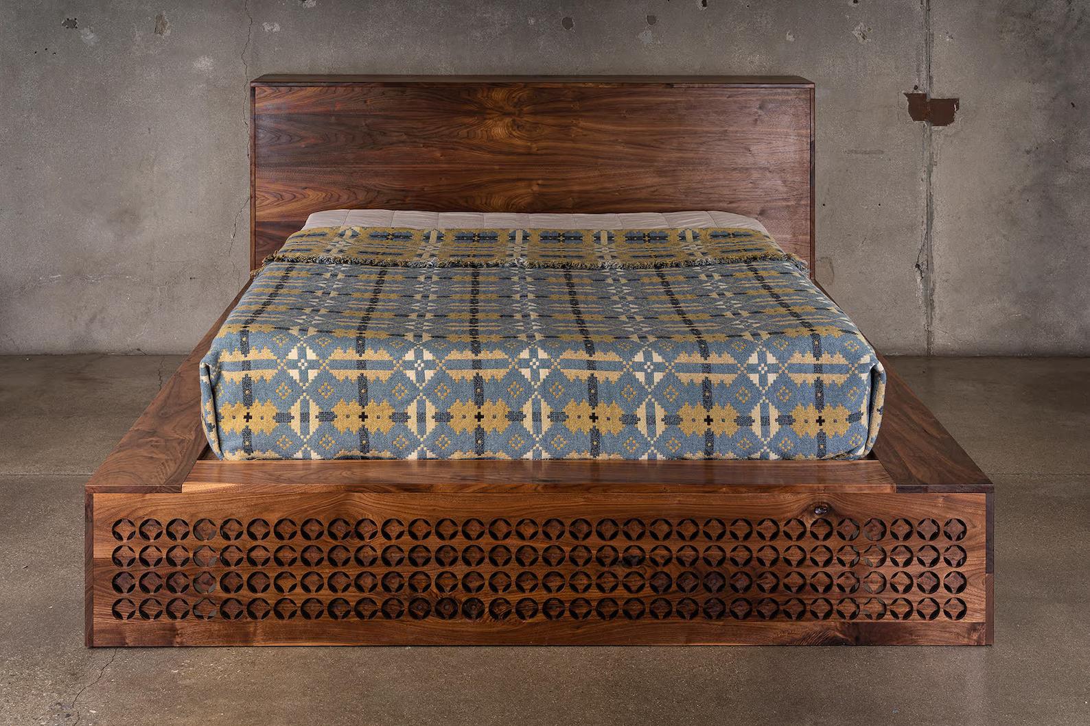 The Hing Bed is a true labor of love. The pattern in the wood is made from a series of overlapping holes carved into the wood. The bed featured here was built from black walnut. The overall footprint for a queen is about 78