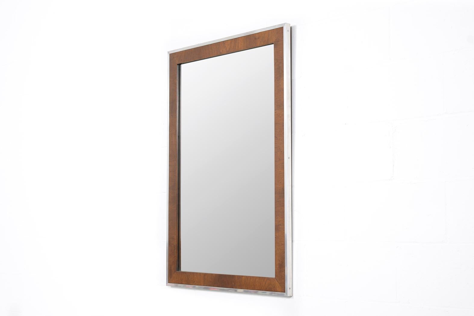 This exceptional vintage Mid-Century Modern wall mirror, expertly crafted from a combination of walnut and aluminum, is presented in great condition and has been meticulously restored by our professional craftsmen. Dating back to the 1960s, this
