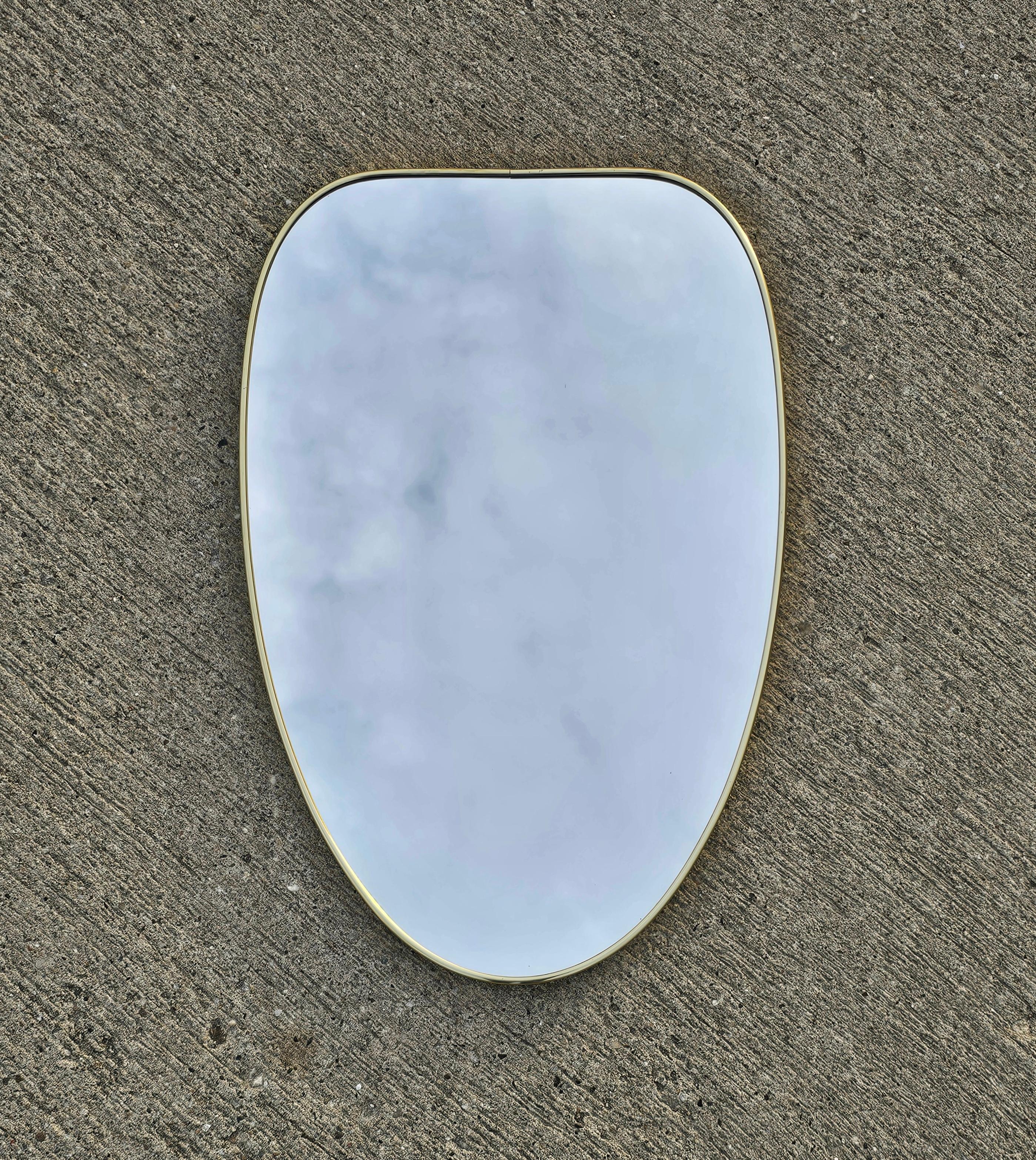 In this listing you will find a striking oval-ish shaped Mid Century Modern 
wall mirror in brass frame in the style of Gio Ponti. Medium format and gorgeous shape make this mirror a hard to find piece. Made in Italy in 1950s.

Mirror is in a very
