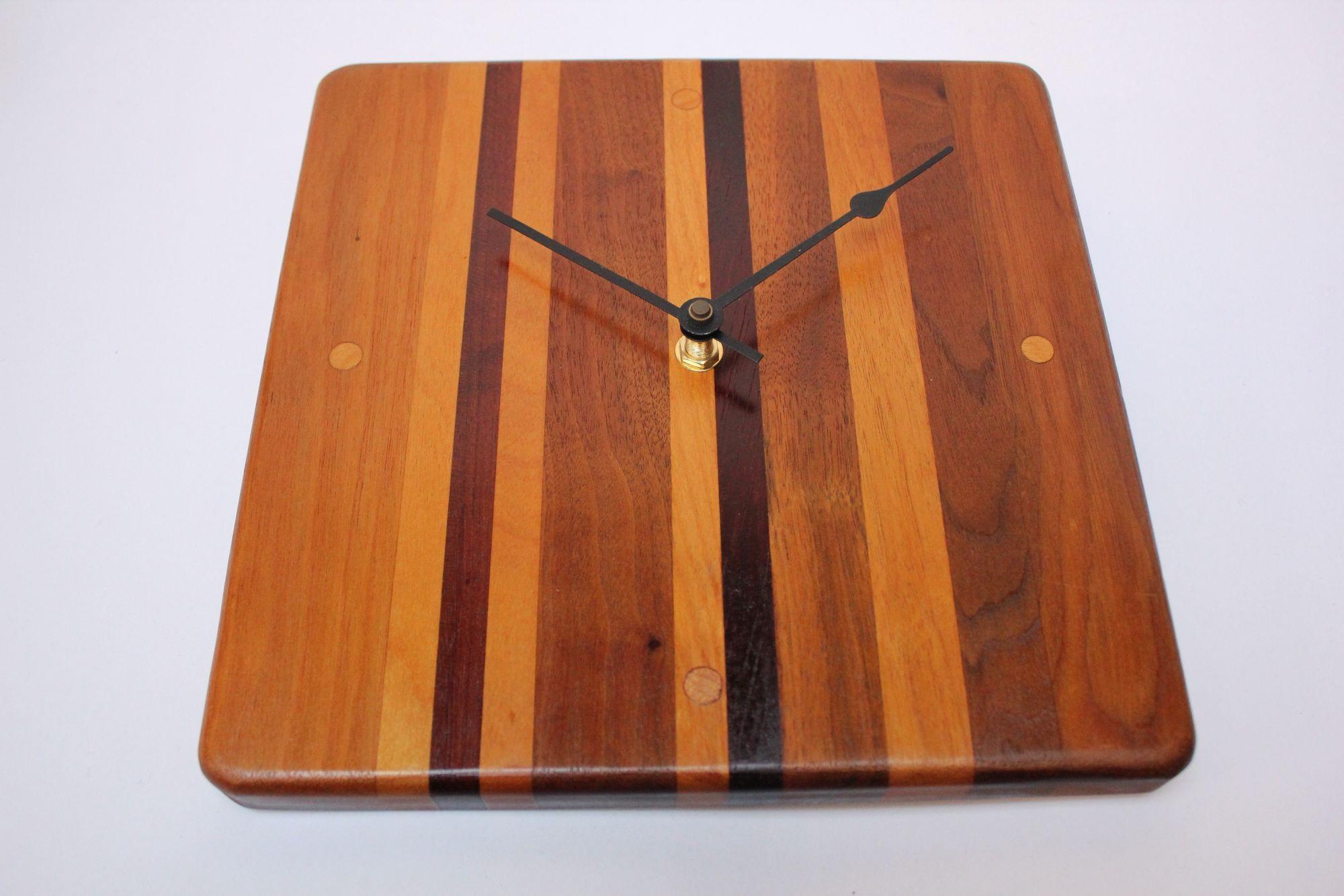 Mid-Century American Modern wall clock composed of teak, English oak, walnut, and rosewood banding. Battery operational (mechanism was converted in the last ten years). Fully functional and in excellent, vintage condition. 
Measures: H: 10