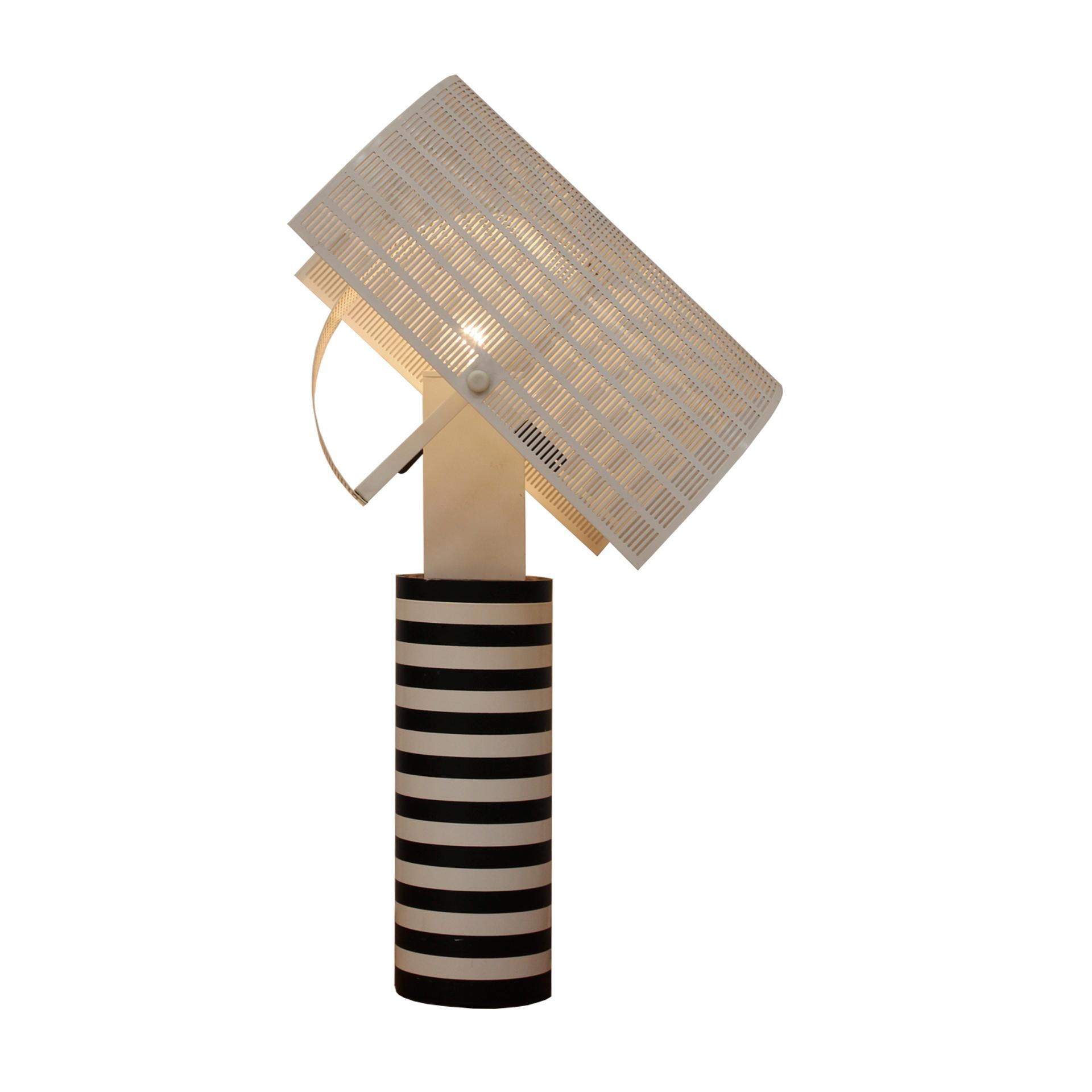 Table lamp mod Shogun designed by Mario Botta for Artemide. Made of steel and aluminun. Adjustable lamp top made of perforated metal sheet. Italy 1980s.

The lamp features a distinct cylindrical shape, meticulously crafted with precise angles and