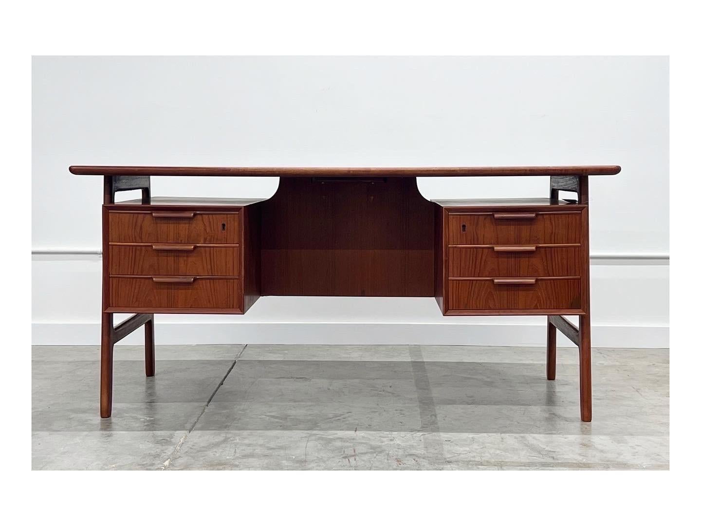 Mid-Century Modern model 75 teak desk by Gunni Omann for Omann Jun Møblefabrik. Floating desk with finished bookcase and compartment for storage on the back, could be easily floated in a room. Amazing legs and six smooth drawers on the front. Patina
