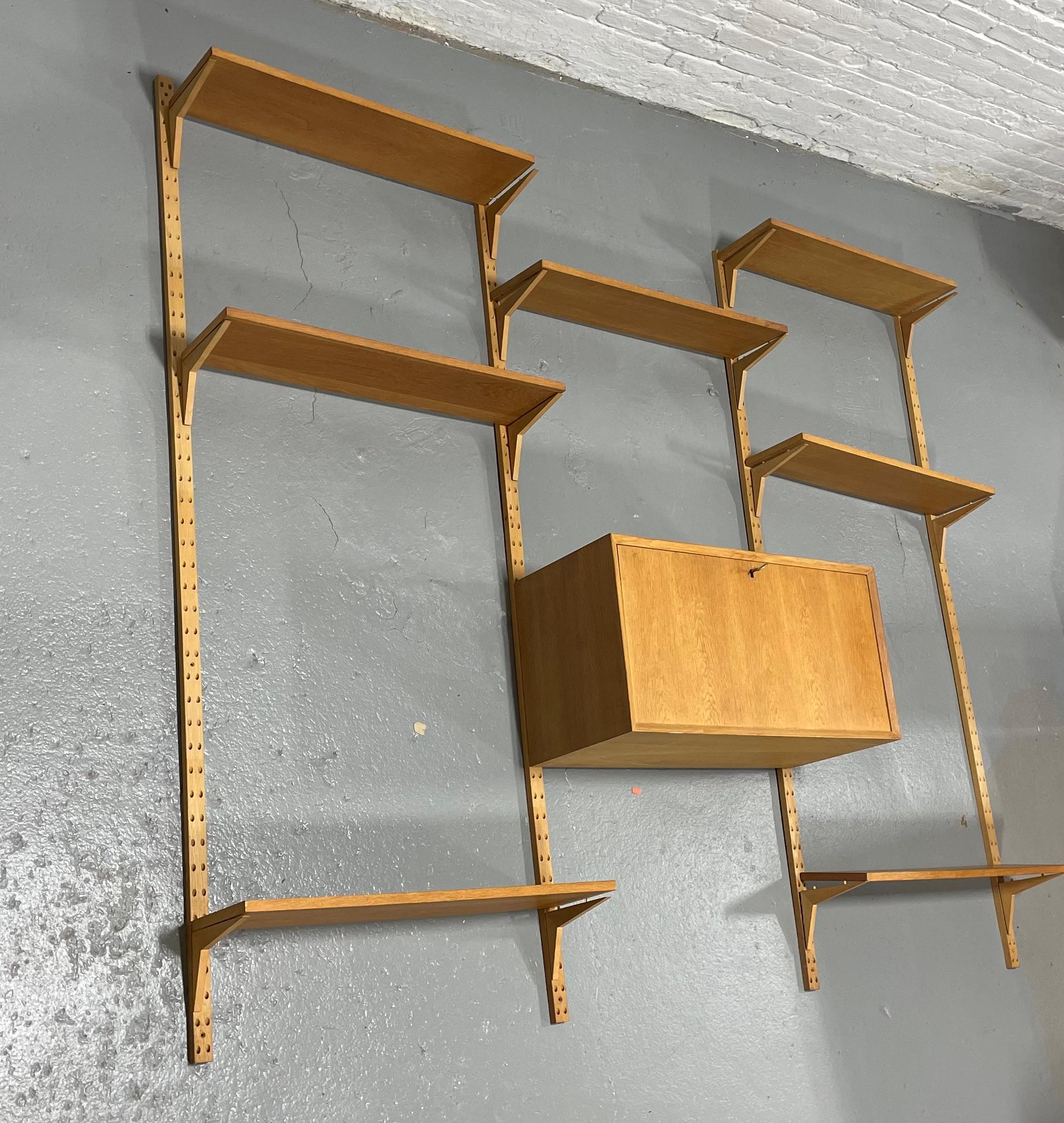 Original Danish Modern Mid Century Cado Wall Unit / Shelving System in hard to find light oak, c. 1960's. Great three bay unit consisting of seven shelves  and one cabinet that can be arranged anywhere on the rails. The cabinet has removable