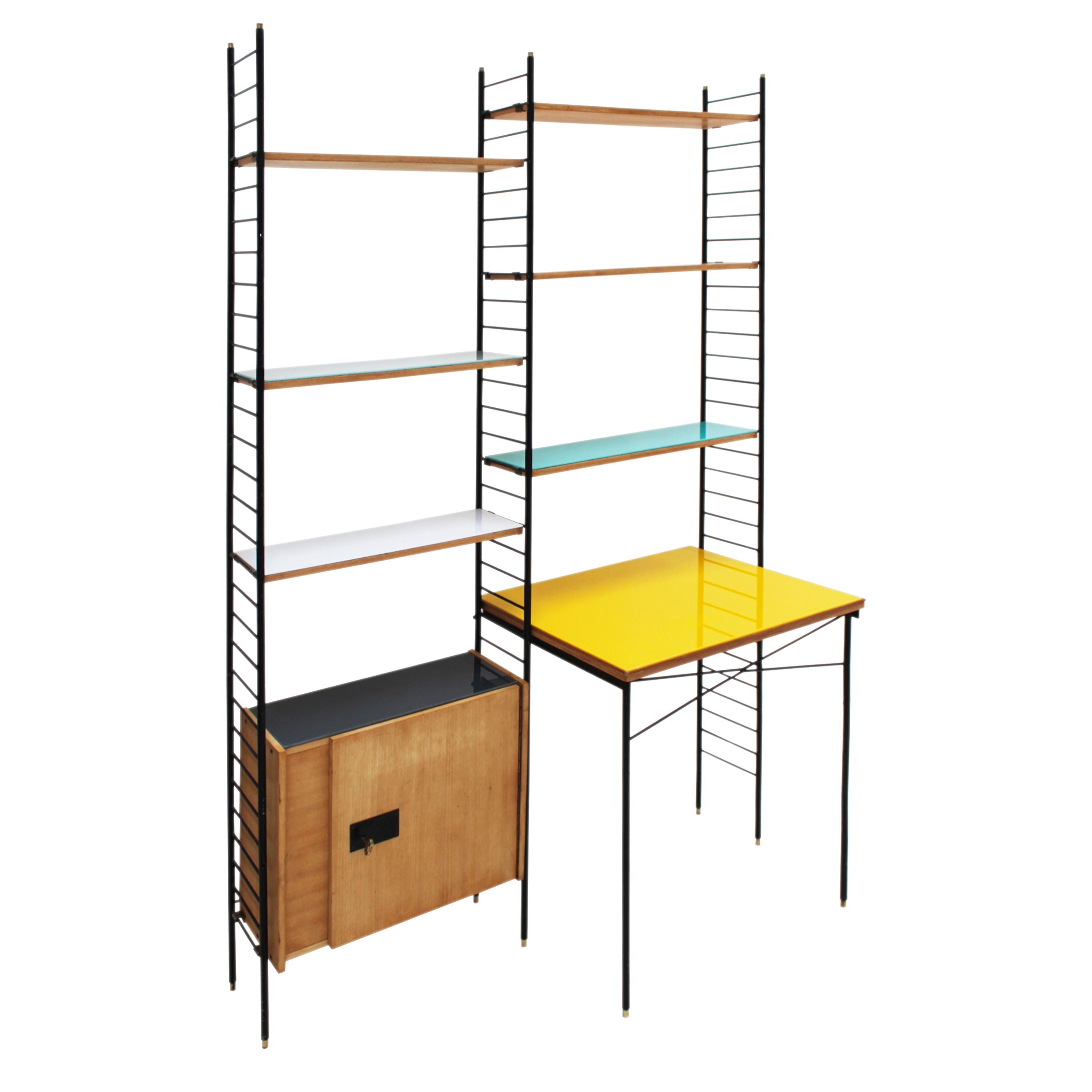 Modular Italian shelving String style, with integrated desk. It is composed of a black lacquered metal structure with brass details that supports the adjustable shelves, a storage module with a door and shelf, and the desk, which are made of birch