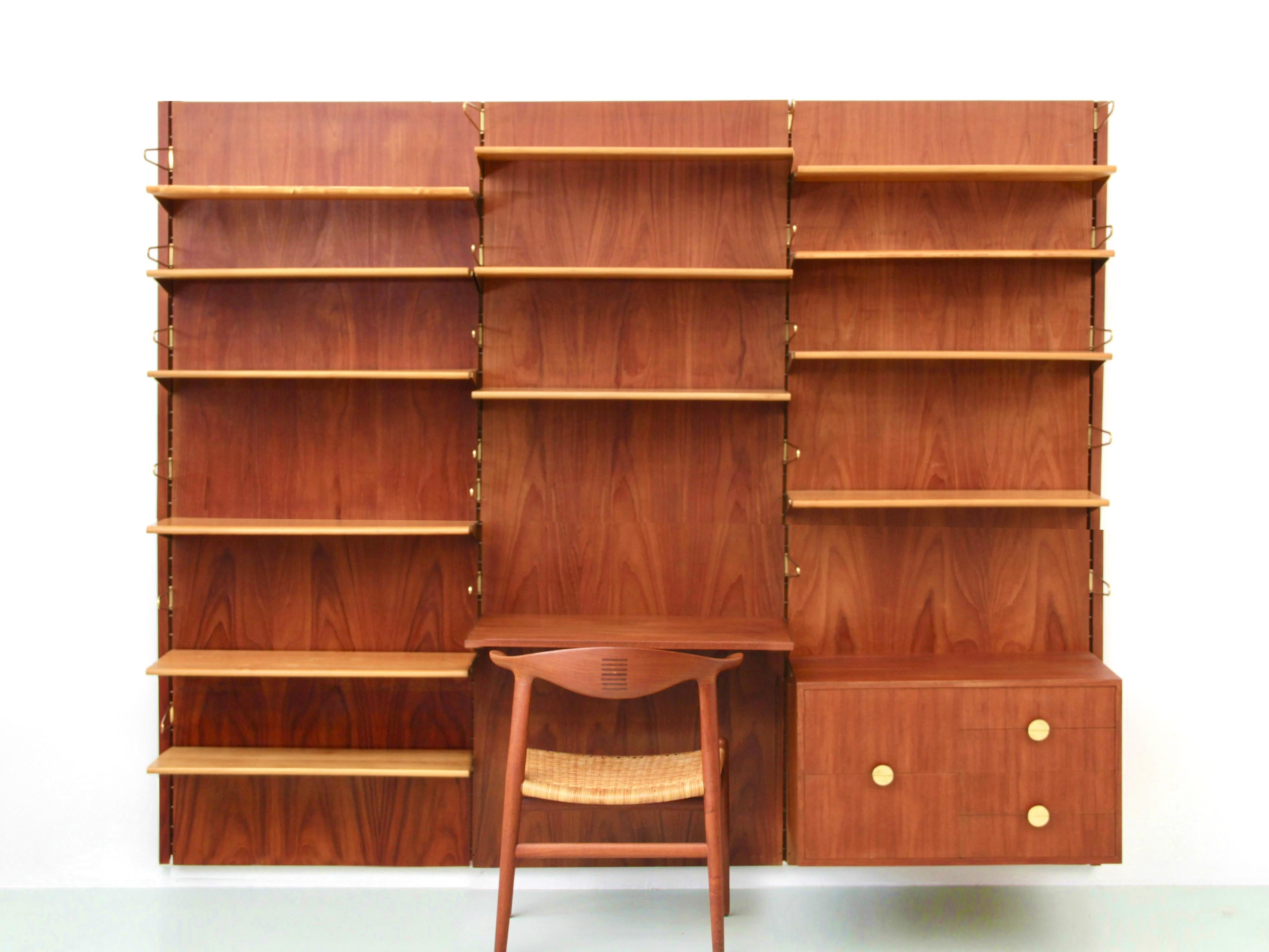Modular shelving system BO71 in teak by Finn Juhl for Bovirke in the 1960s. Comprising 3 columns, 4 rules, 1 unit with 6 drawers, a writing desk, 13 Oregon pine shelves, and 22 brass bookends. Brass bracket system.

H 200 cm. Total W 234 cm. Shelve