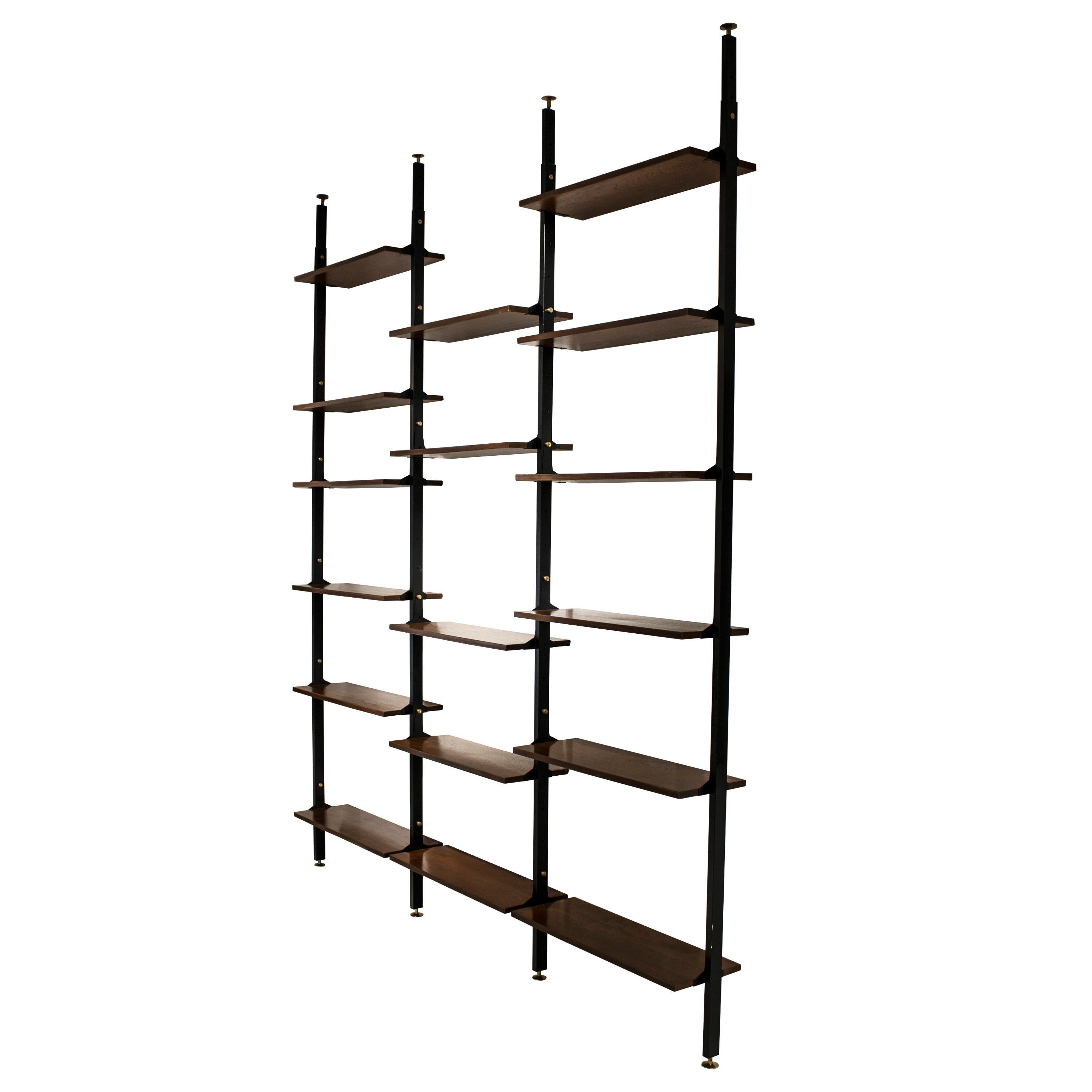 Mid-Century Modern modular shelving. It consists of a height-adjustable black lacquered metal structure with brass lozenge details and teak wood shelves.