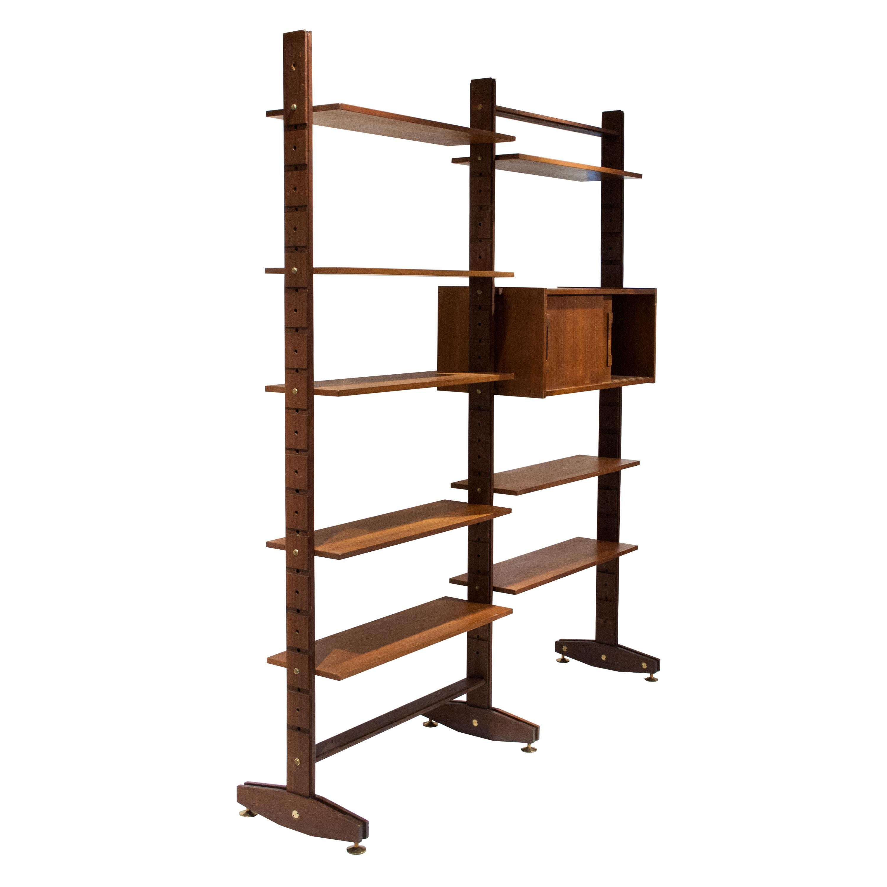 Mid-Century Modern modular bookcase made of teak wood. The bookcase is composed of three foots where you can attach the shelves and a 2 sliding door storage cabinet. Screws and adjustable feet made of brass.