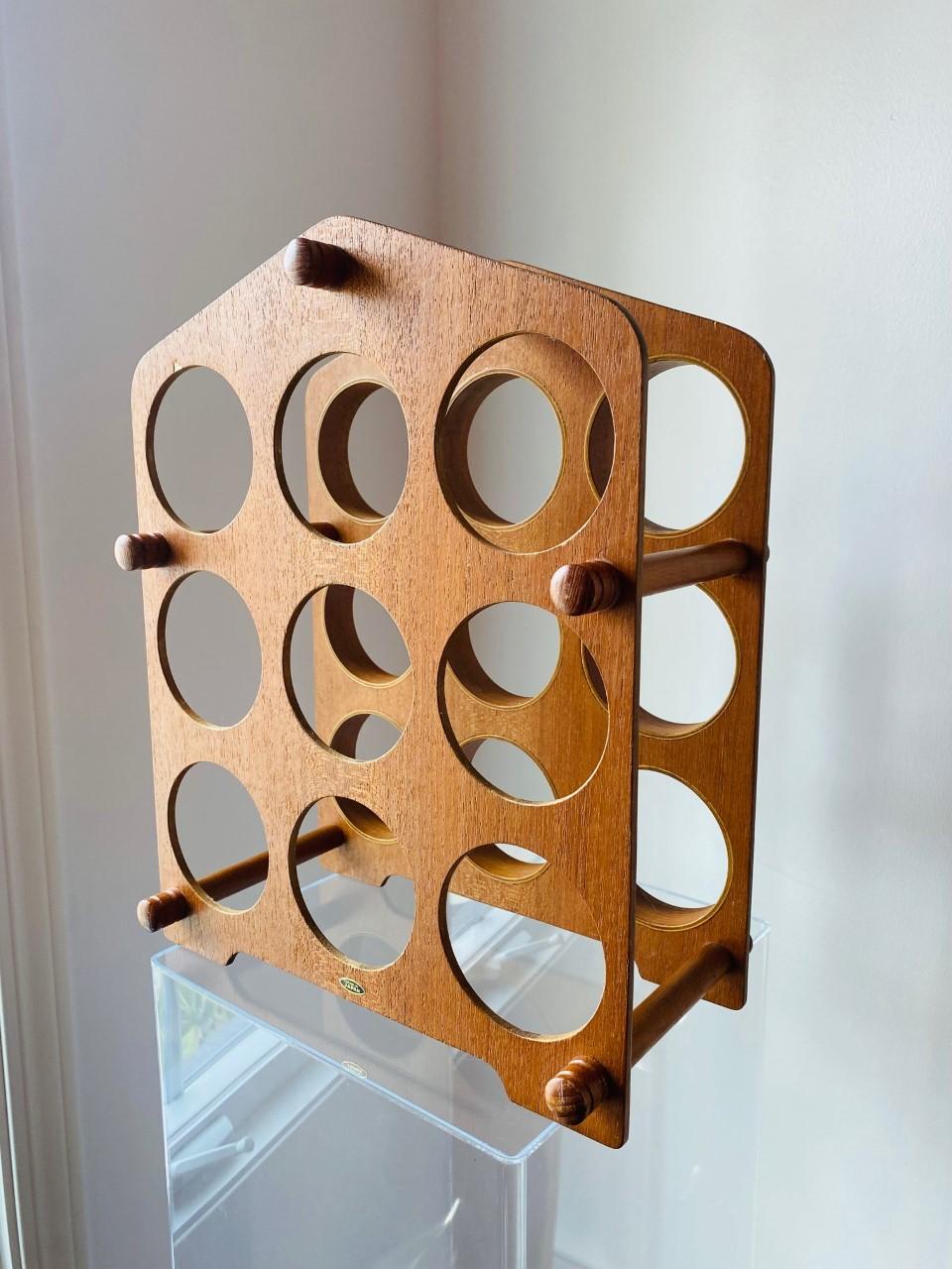 Vintage teak wine rack that embodies the minimal scandinavian cool of Mid Century. This piece embodies a very cool design in rare vintage molded teak. Capacity for 9 bottles, makes it a must have for your bar. Minimalist and cool with signature made