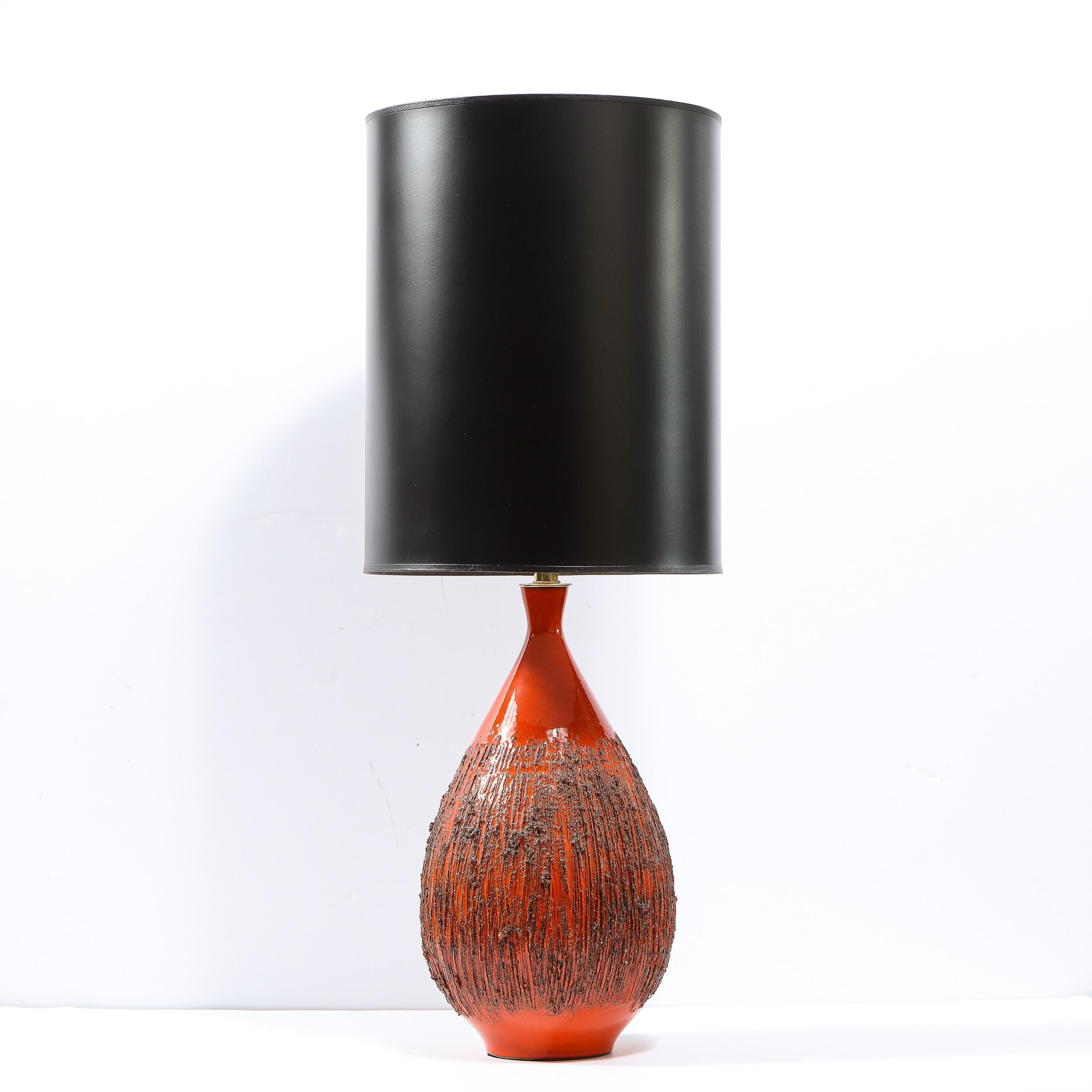 This exquisite Mid-Century Modern table lamp was designed by Lee Rosen for Design Technics in the United States circa 1960. It features a tear drop form in a volcanic molten orange red glaze replete with an organic hand carved vertical striated
