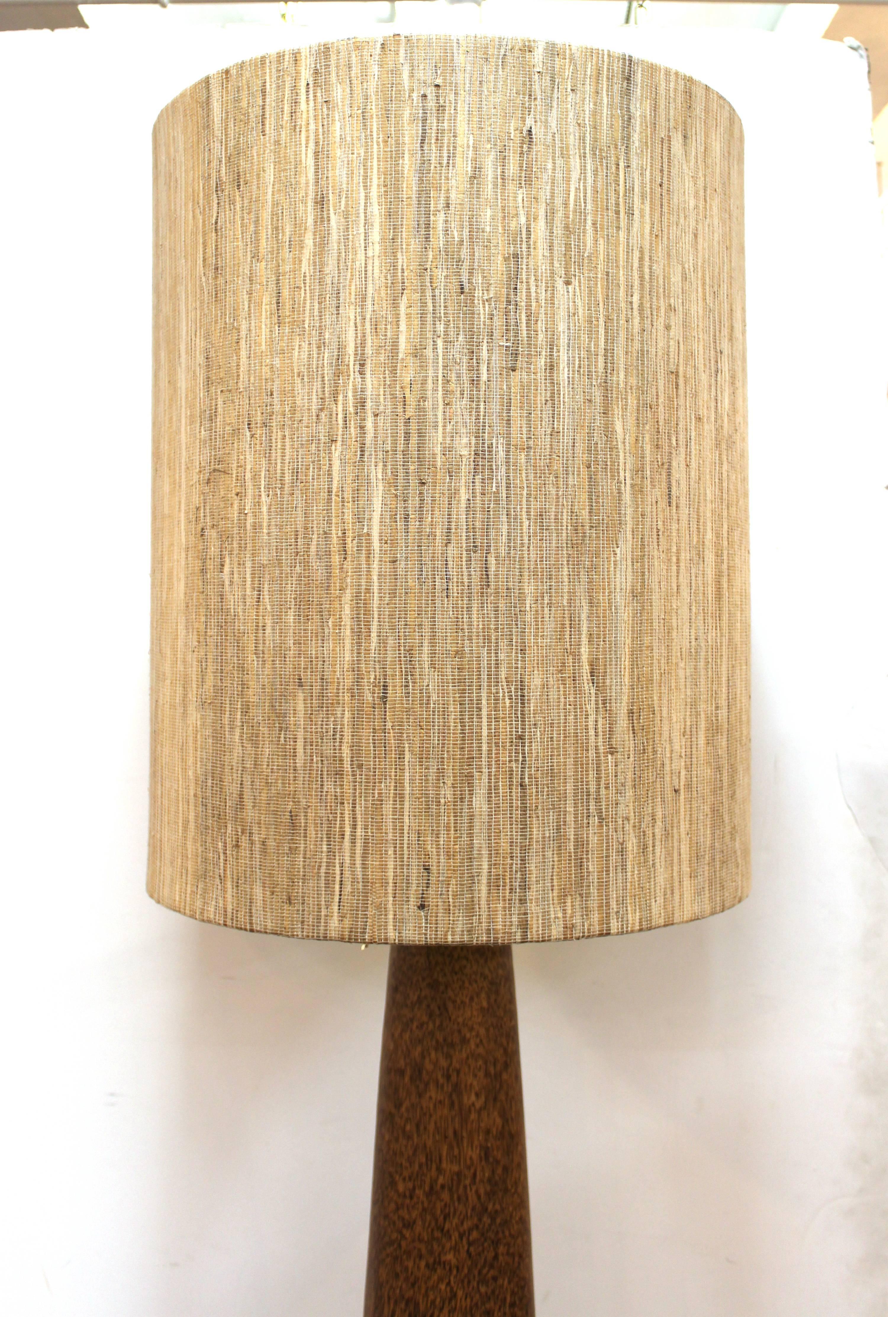 Mid-Century Modern floor lamp with trunk column body. Crafted in light wood with a large woven reed shade. Some pulls to the shade material with wear appropriate to age and use. The lamp is in good vintage condition. 

With the shade the height of