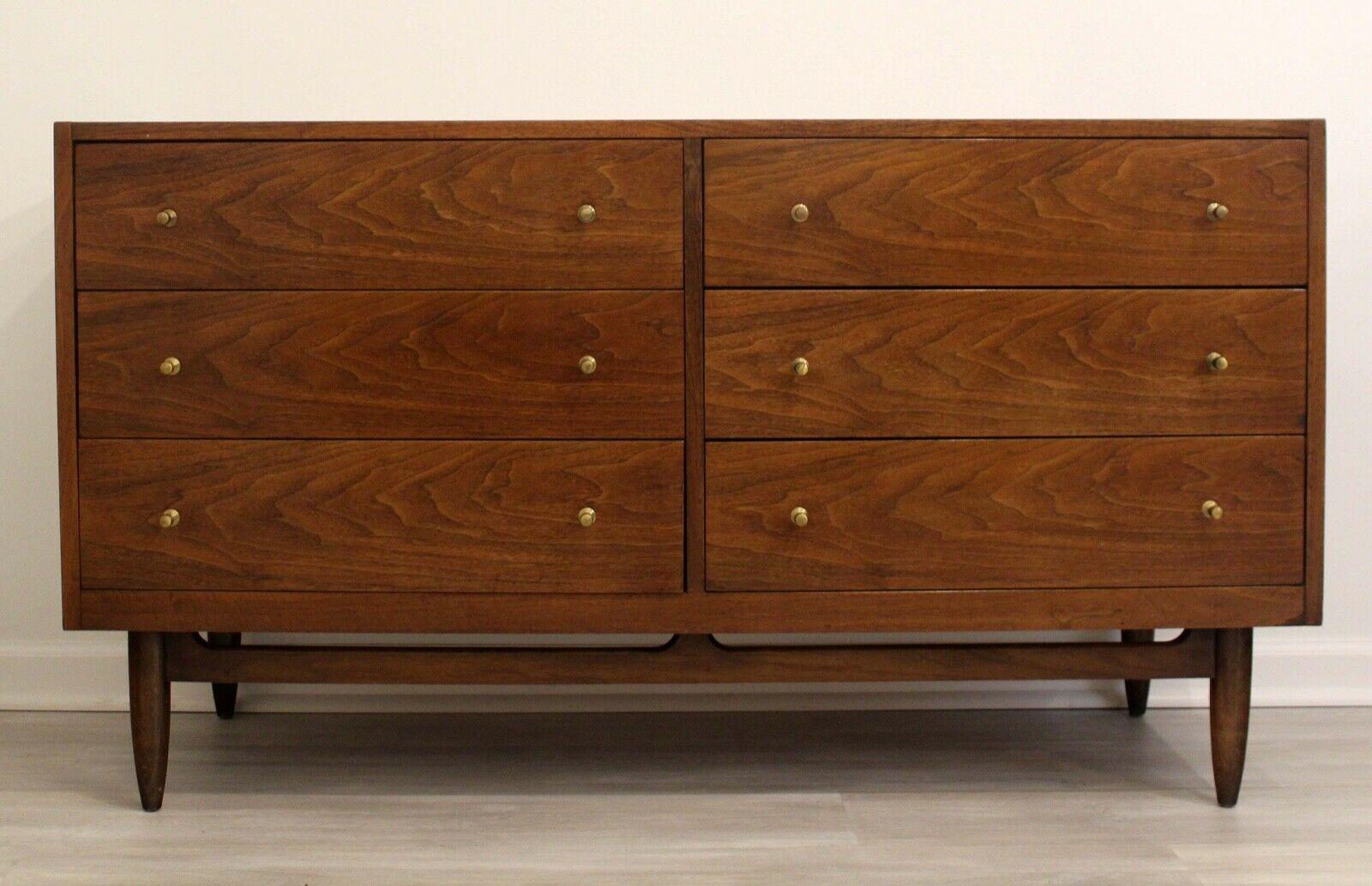 This lovely, Mid-Century Modern credenza storage unit made of walnut offers six drawers with dividers or the ultimate organization in any dining room or bedroom. Low profile brass pull finish this piece and adding to its modern, eclectic