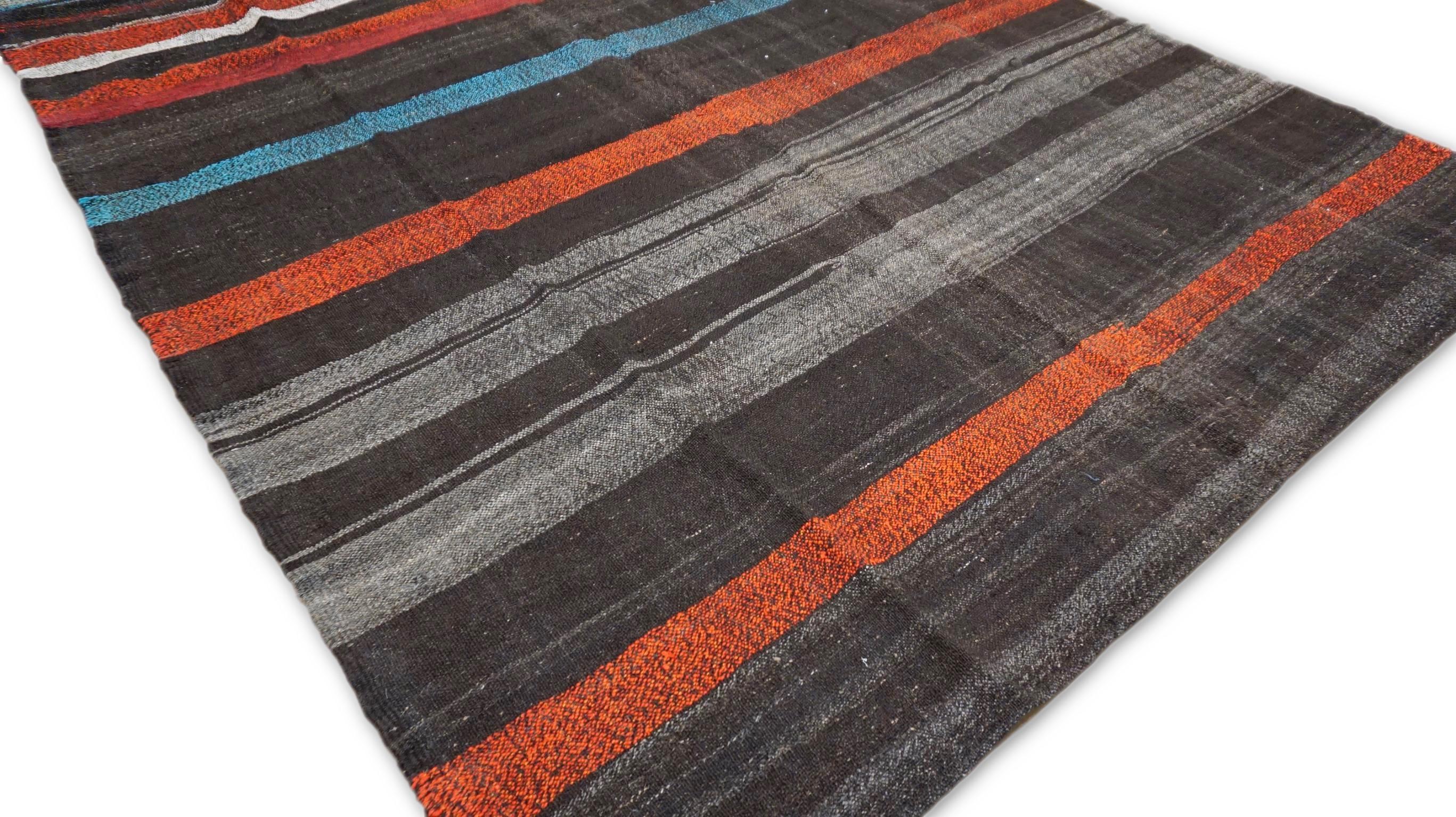 Questo straordinario kilim in lana vintage incarna il fascino senza tempo dell'artigianato tradizionale con un tocco moderno. Caratterizzato da audaci strisce orizzontali nelle vivaci tonalità del rosso intenso, del blu, dell'arancione e del