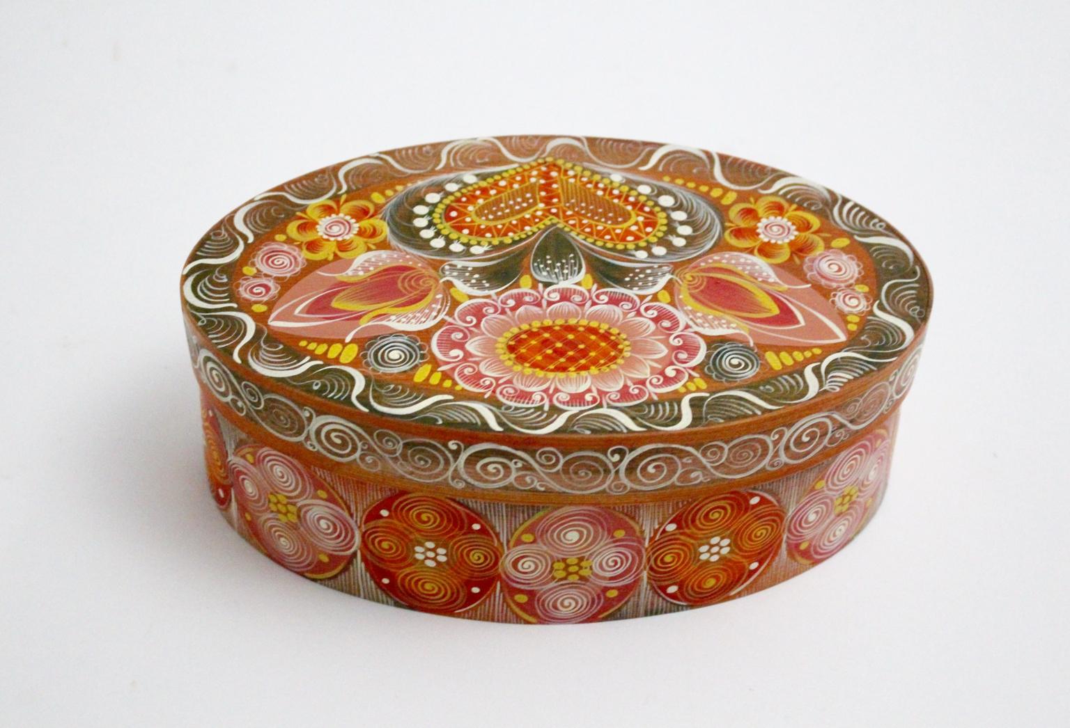 Die Folk-Art-Splintbox zeigt mehrfarbige, handgemalte ländliche Dekore wie Blumen und Herzen.
Es wurde in den 1950er Jahren in Österreich entworfen und hergestellt.
Die ovale Schachtel besteht aus einem Bodenteil und einem Deckel.
Der Zustand ist