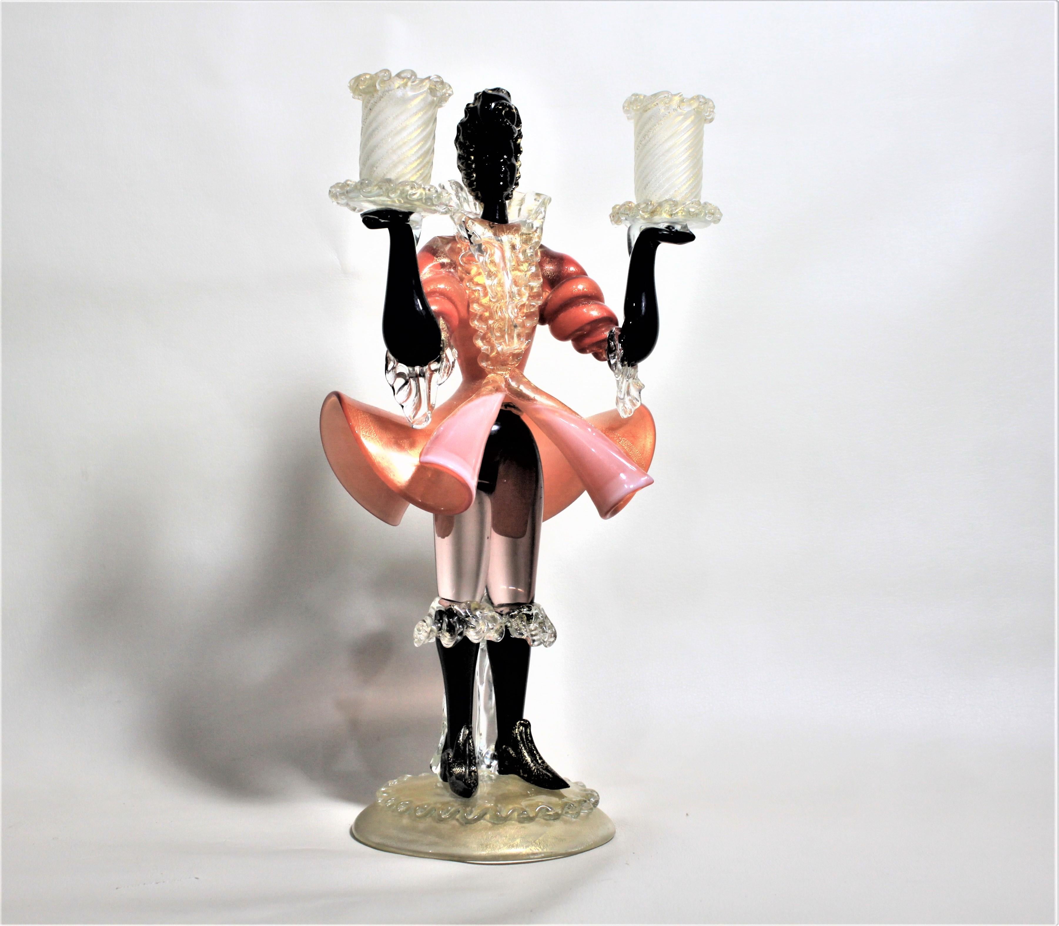 This midcentury Murano art glass candlestick is unmarked but most likely made by Barovier. The candlestick is a figural servant dressed in the high fashion of the French Renaissance period with outstretched arms holding a candle with each arm. The