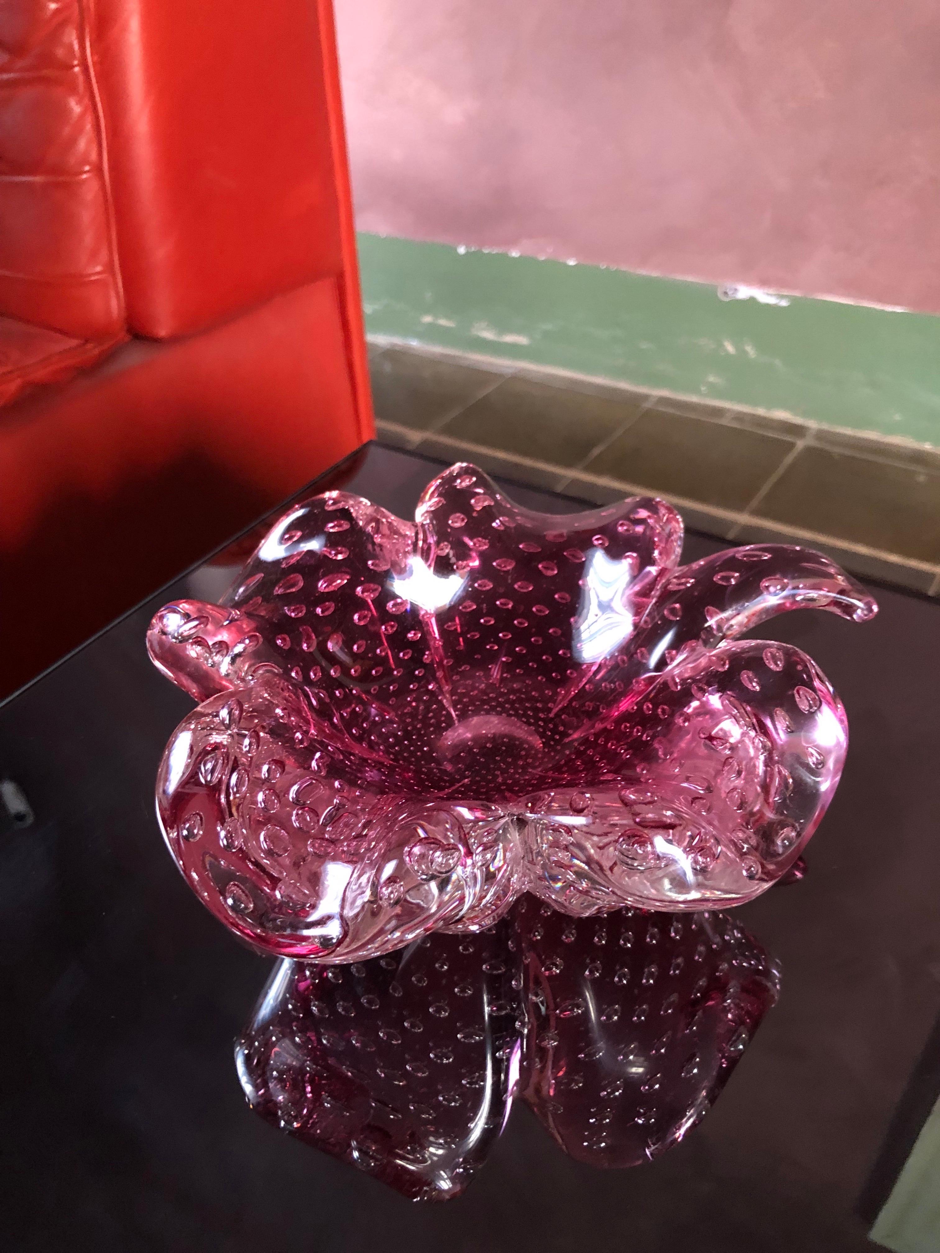 Este cenicero vintage de Murano es un raro hallazgo para coleccionistas y amantes del cristal italiano.
Soplado a mano en grueso cristal rosa transparente, tiene la forma de un trébol de cuatro hojas que simboliza la suerte y el encanto. Pequeñas