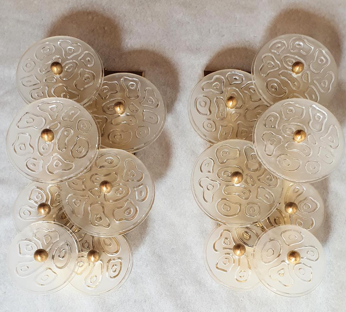 Mid-Century Modern clear Murano glass and brass sconces by Vistosi, Murano, Italy, 1960s, two pairs available.
Sold and priced by pair.
The vintage sconces have handmade thick, clear and frosted Murano glass discs, with a nice organic pattern in