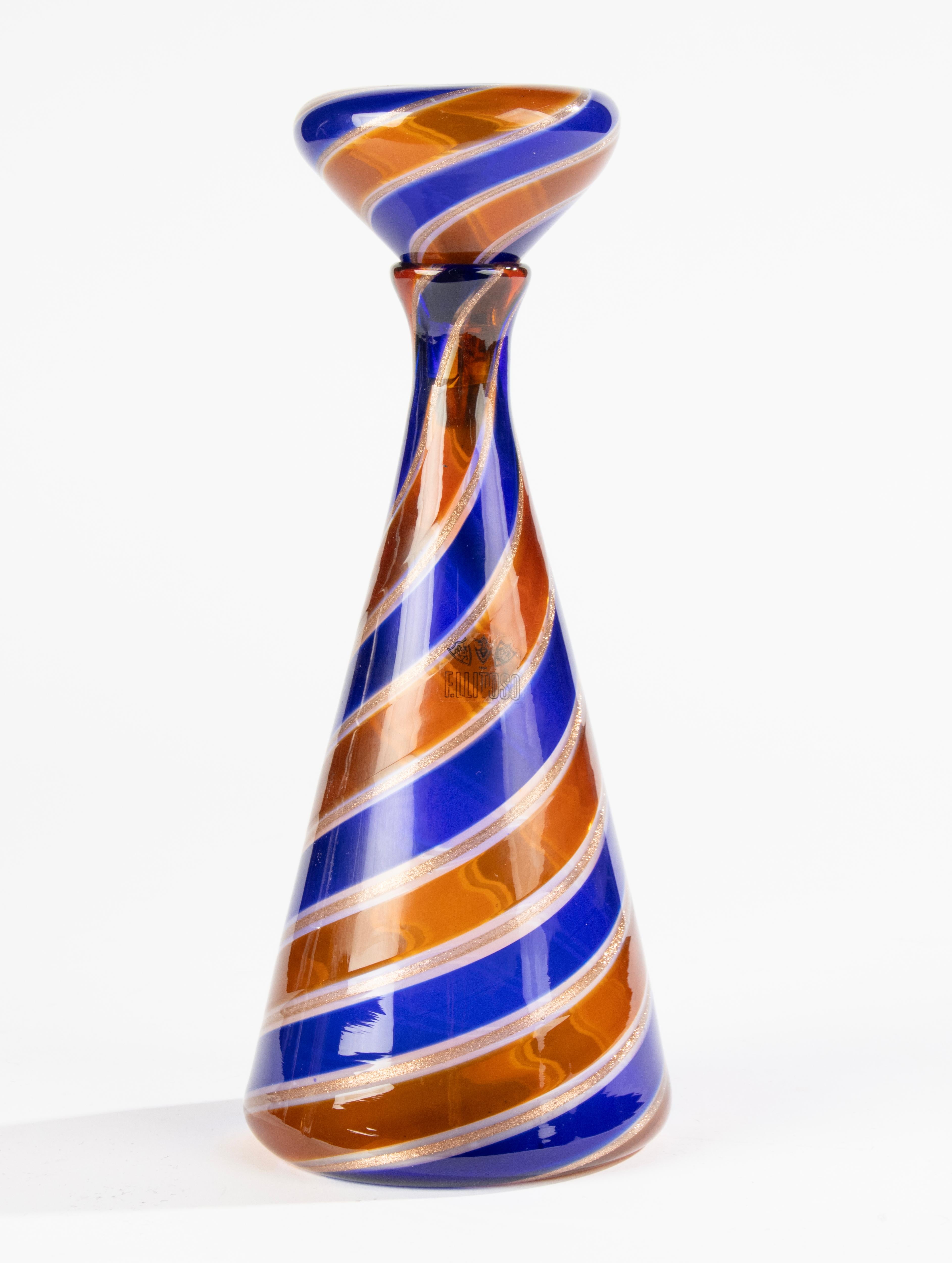 Une belle carafe en verre d'art, fabriquée par le designer italien Fratelli Toso.
Magnifique palette de couleurs, avec des tourbillons bleu foncé, ambrés et dorés.
La carafe porte une étiquette originale de Fratelli Toso.
La carafe est en très bon