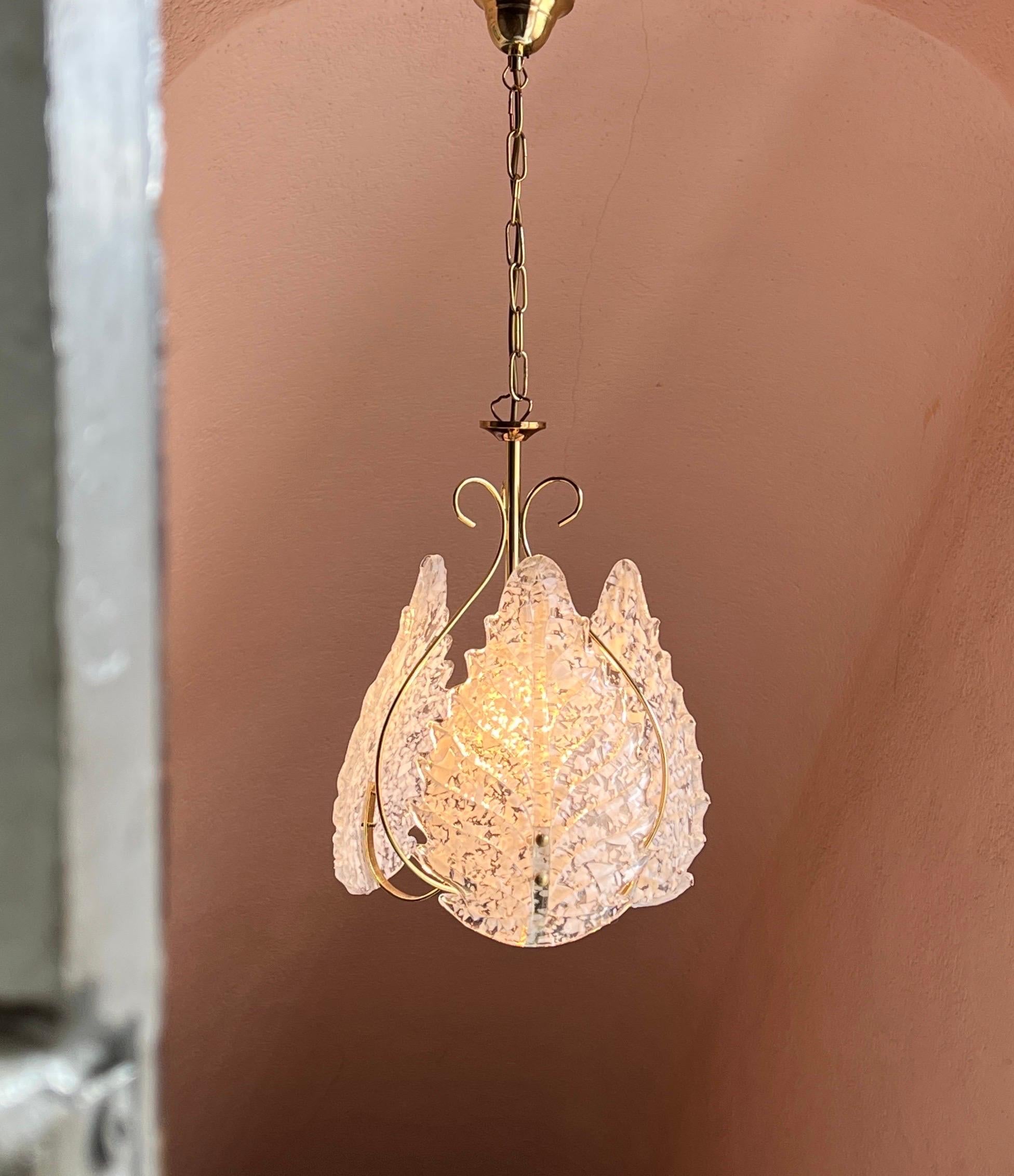 This elegant Murano glass pendant light was crafted in the 1970s, featuring a refined yet intricate design. Three beautifully hand-blown Murano glass leaves are set into a gold-coated metal frame, creating a striking balance between simplicity and