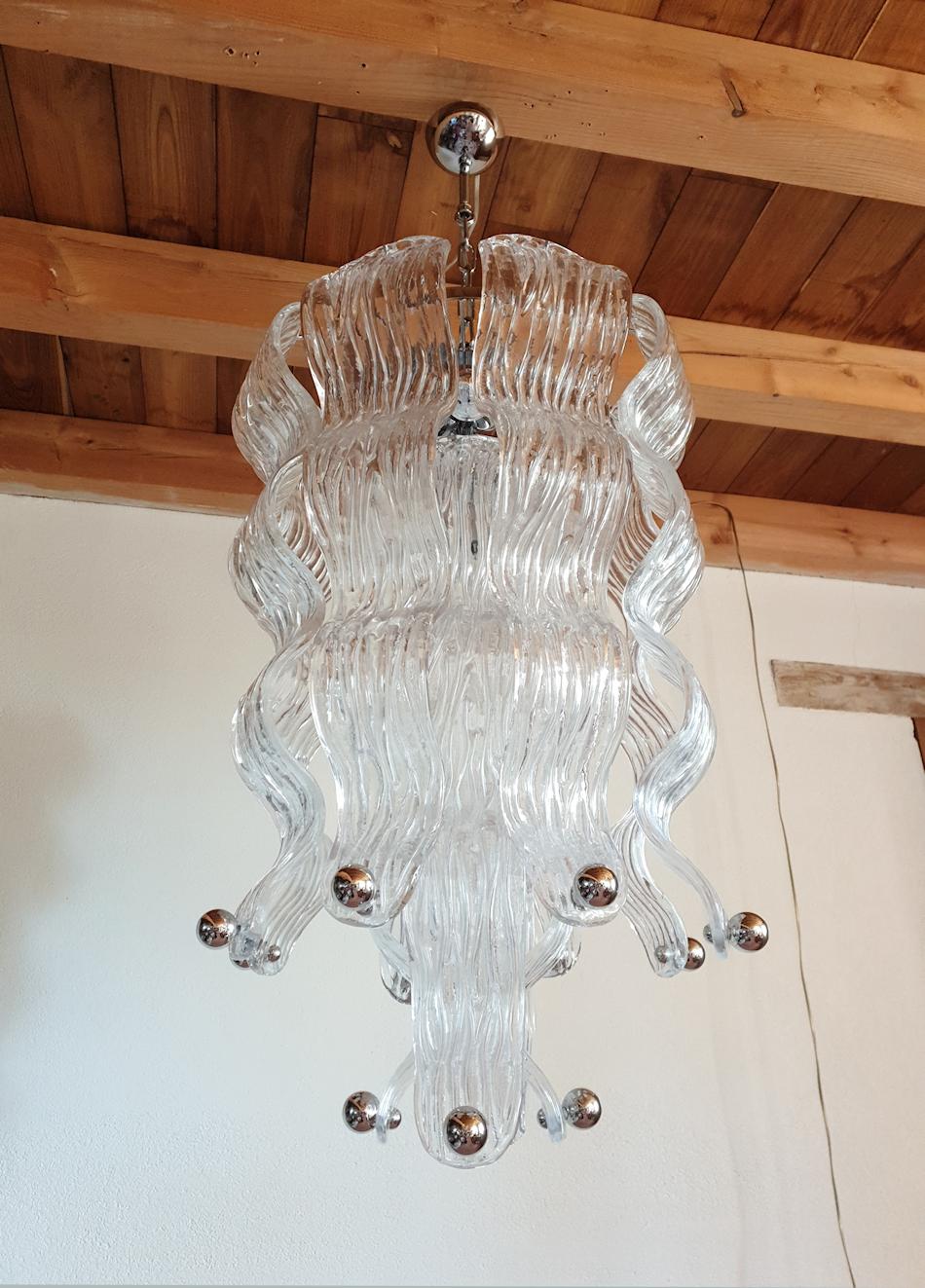 Tall vintage modern style Murano glass chandelier, with chrome fittings, attributed to Mazzega, Italy 1970s.
Two chandeliers available, identical; sold and priced individually.
The Mid-Century Modern pendant light is made of large clear textured