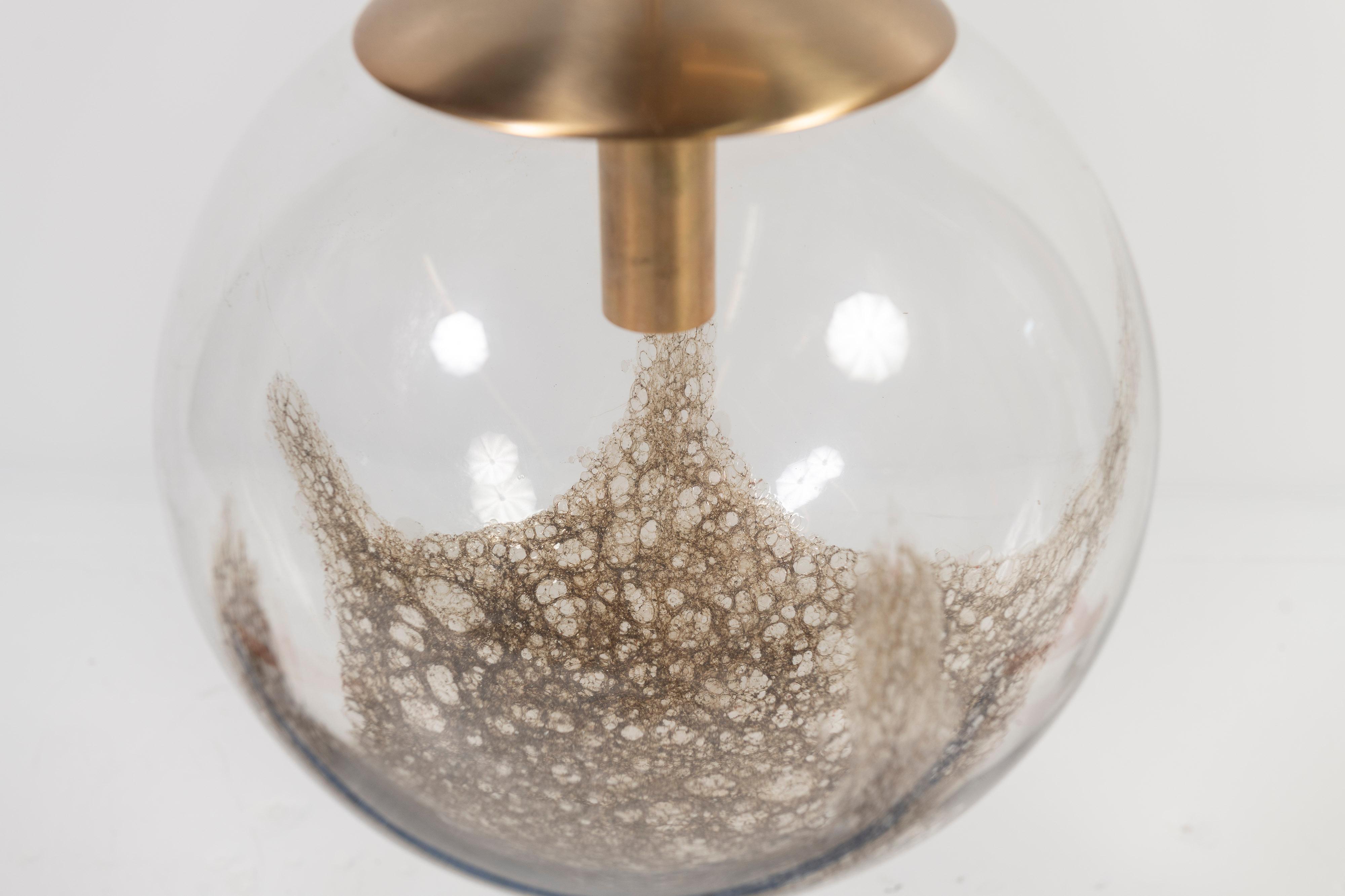 Gorgeous Murano glass globe is splattered with bronze colored effects on the interior and designed by Carlo Nason for Mazzega. The pendant shimmers when lit, casting a lovely reflection all around.   The fixture hangs from a brass canopy and has an