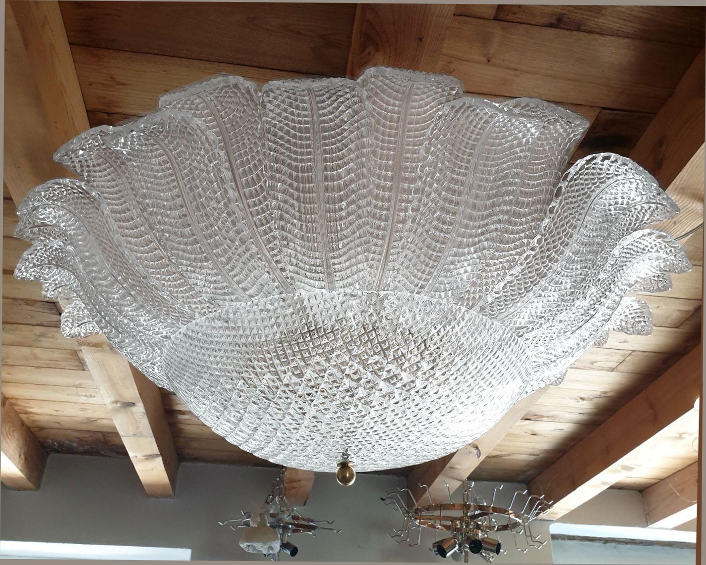 Très grand lustre en verre de Murano, attribué à Barovier&Toso, Italie, années 1970.
L'immense lustre est composé de feuilles de verre de Murano transparentes, avec un motif de grille, ce qui les rend translucides à travers la lumière.
Ce motif est