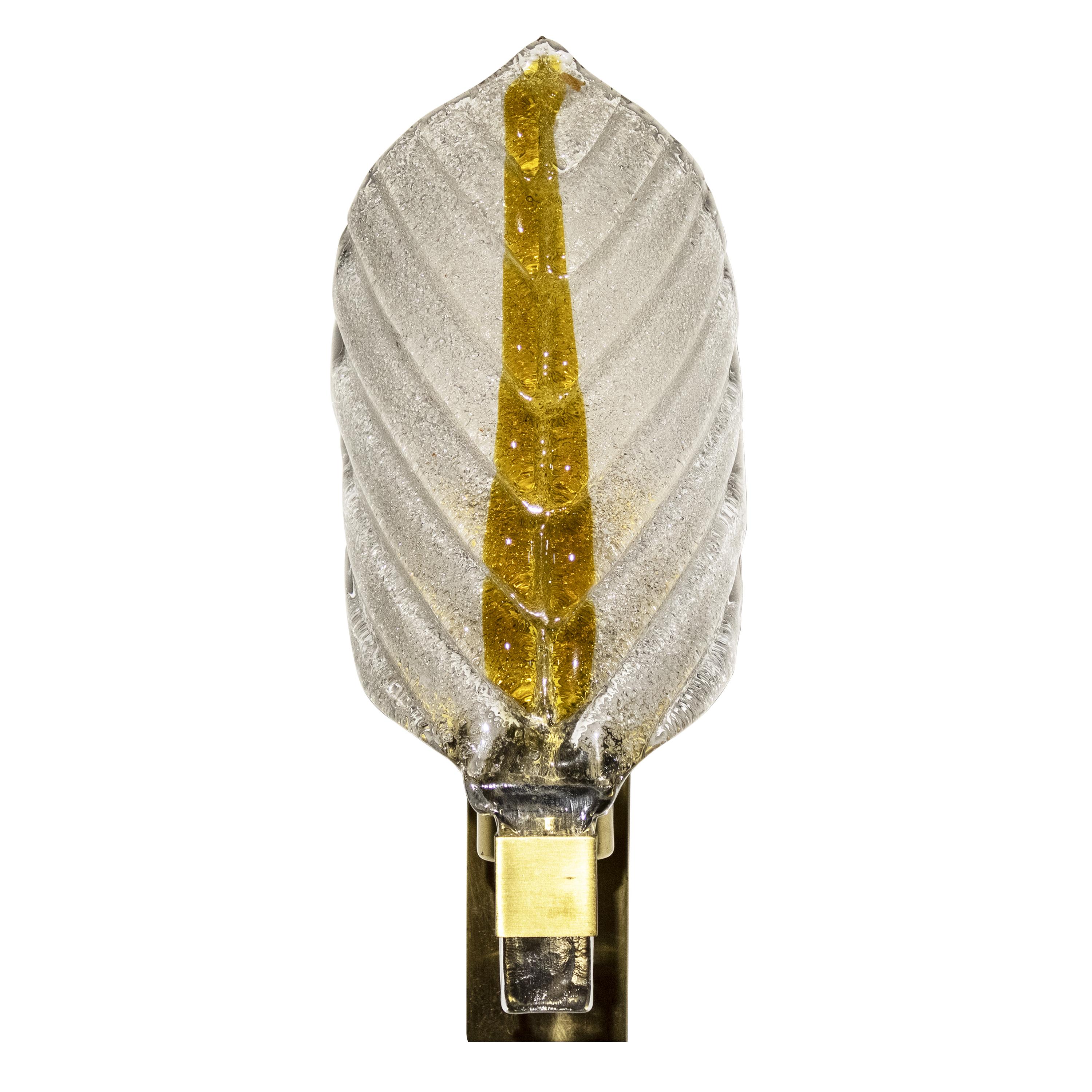 A sculptural hand-carved and hand-molded leaf-shaped Murano glass sconce with a rectangular brass structure.
The lamp consists of semi-transparent ice frost bicolor glass painted with an auburn line in the center. Detailed with vertical twisted